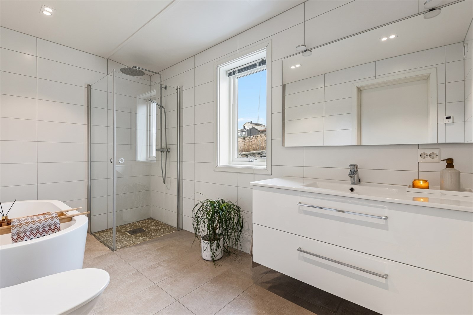 Badet i andre etasje er stort og lekkert innredet med grå fliser på gulvet og hvite fliser på vegg. I gulvet har man vannbåren varme for ekstra komfort. Galleribilde