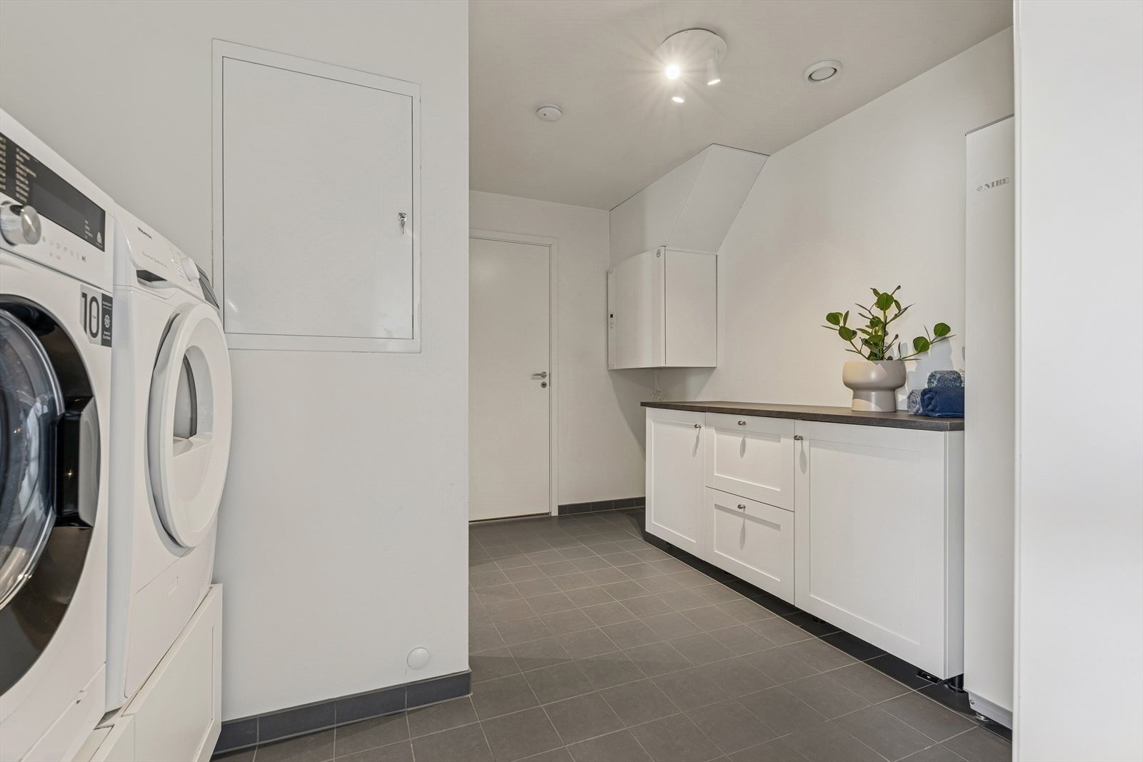 I tilknytning til gangen finner man et vaskerom med bi-inngang, hvor man kan gå tørrskodd inn fra carporten. Flislagt gulv med vannbåren gulvvarme. Et kjekt rom for barnefamilien når de minste i familien kommer hjem med møkkete klær og sko. Galleribilde