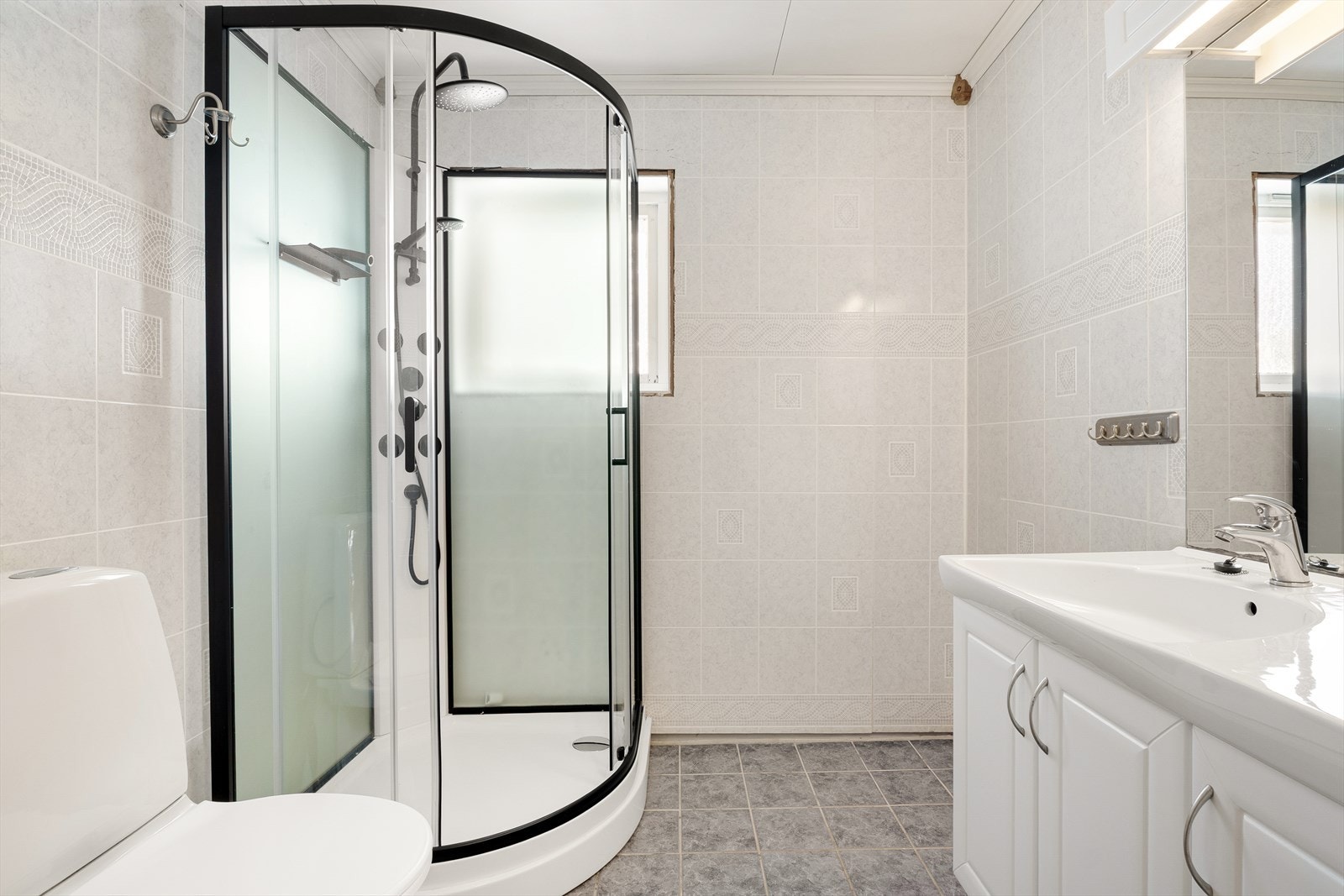 Badet har fliser på gulv og våtromsplater på veggene, med varmekabler som gir en lun og behagelig varme. Galleribilde