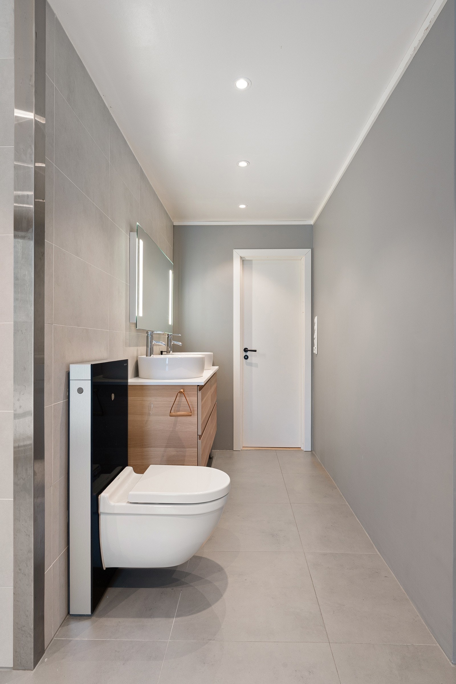 Moderne baderom med vegghengt wc, tidsriktig servant med skuffer og badekar. Galleribilde