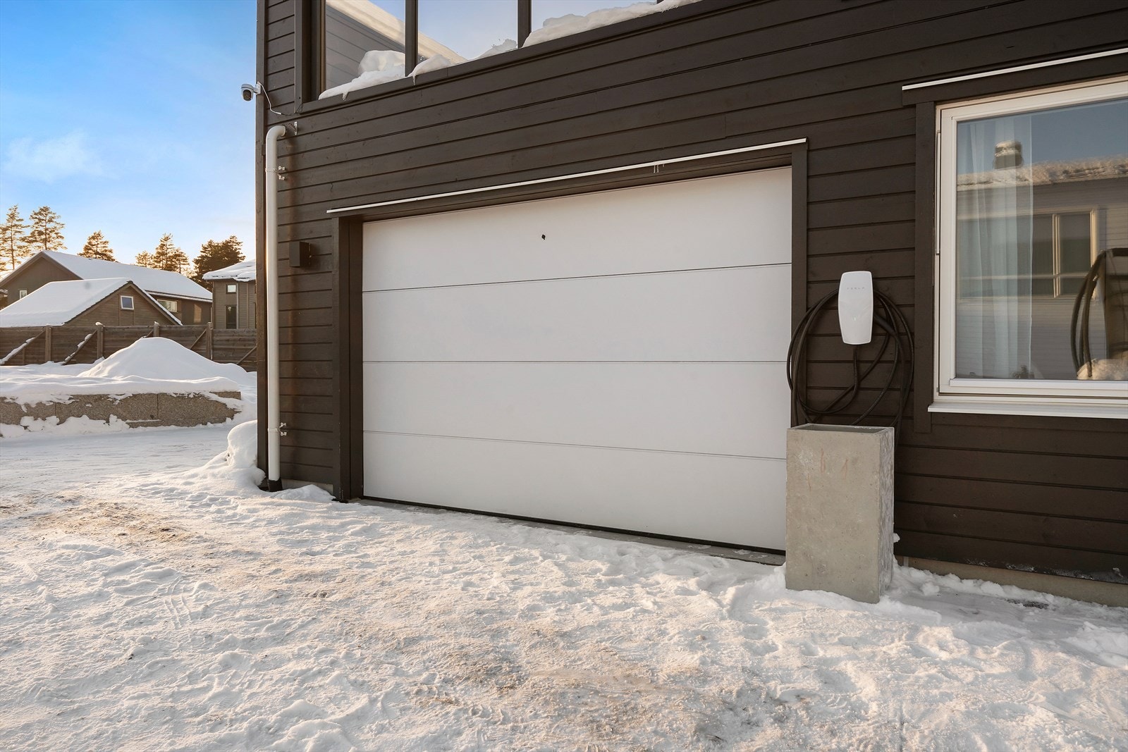 Parkering forekommer i gårdsplass og i integrert garasje med elbillader montert på yttervegg. Galleribilde