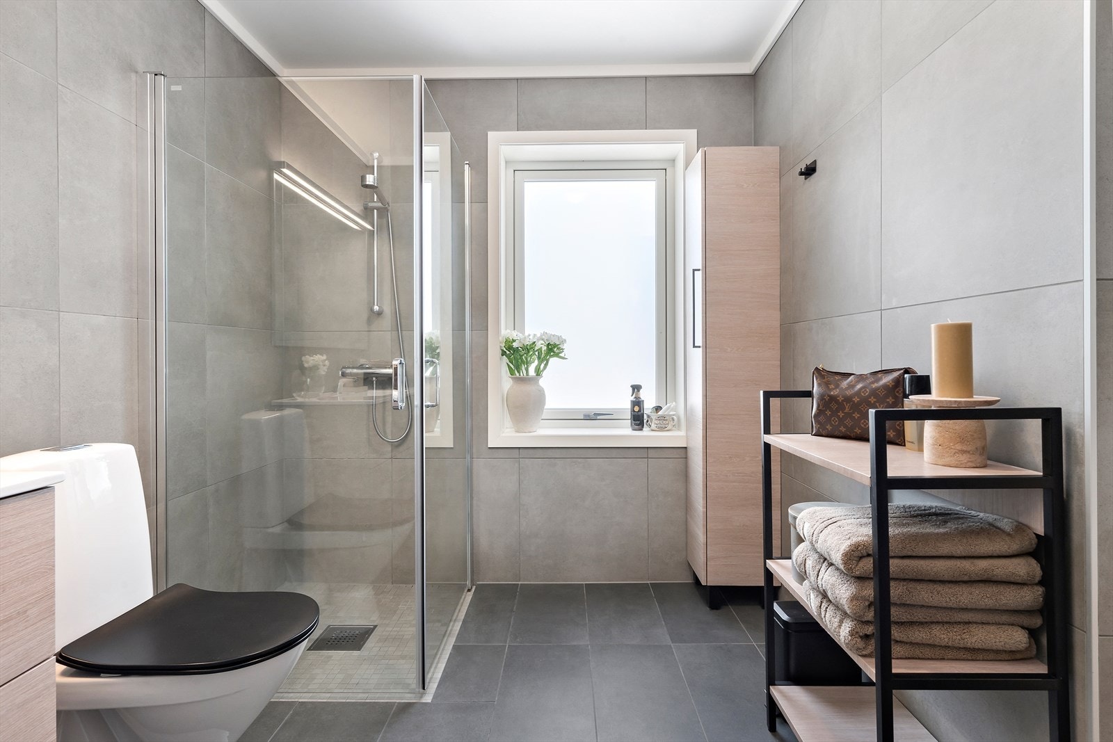 Badet er innredet med baderomsinnredning med heldekkende nedfelt servant med oppbevaring, speil, toalett og dusjhjørne. Galleribilde