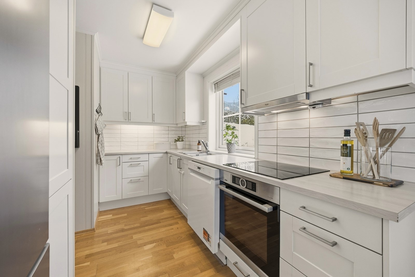 Pent kjøkken fra Sigdal med profilerte fronter, flislagt over kjøkkenbenk og benkeplate i laminat Galleribilde