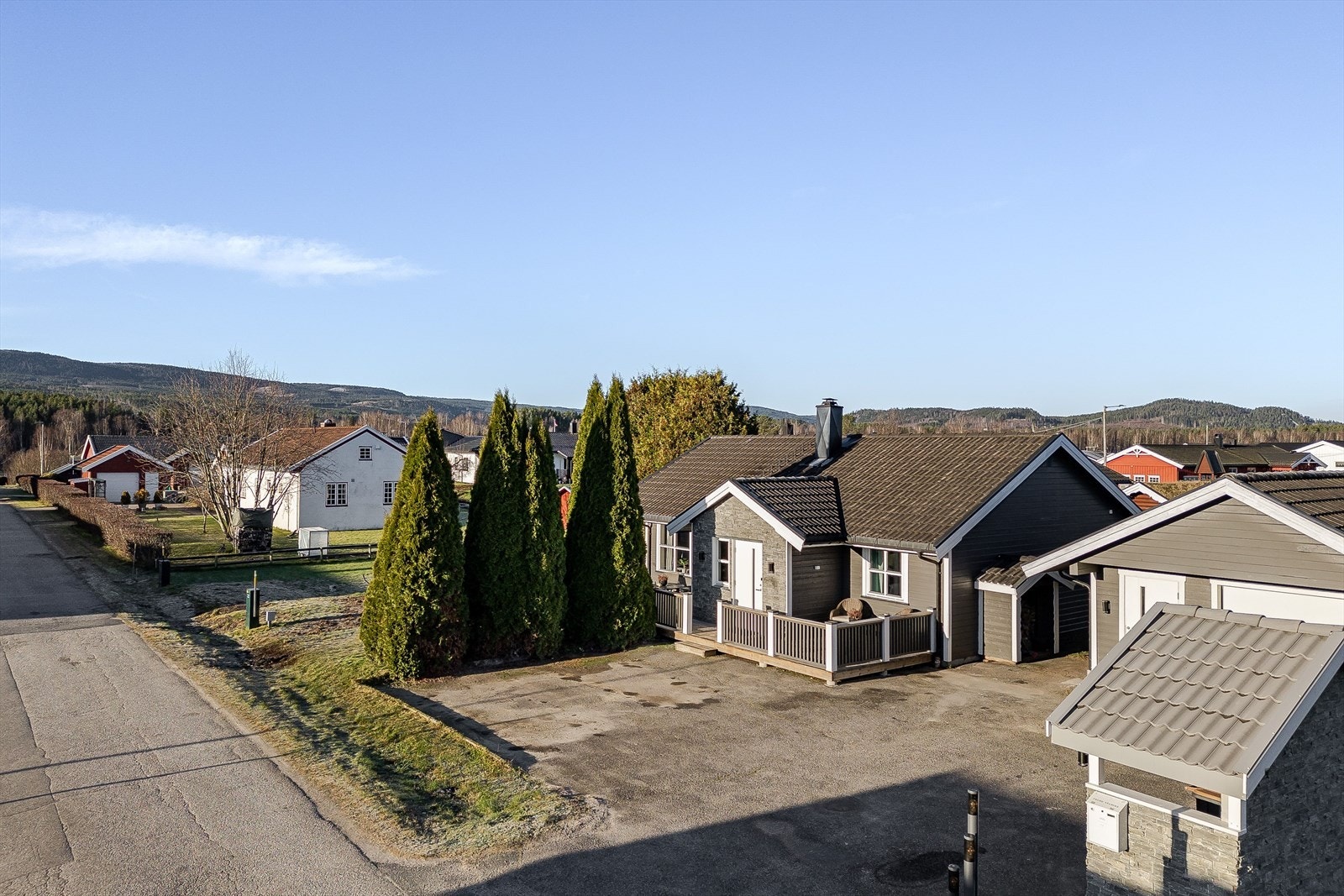 Fasaden har liggende trekledning og skiferstein ved inngangen, med godt vedlikeholdt utendørsbelysning. Galleribilde