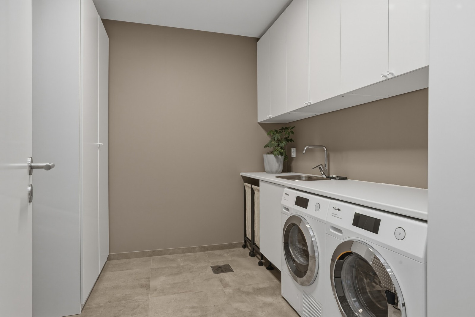 Separat vaskerom med innredning med nedfelt vaskekum og blandebatteri, og opplegg for vaskemaskin/tørketrommel Galleribilde