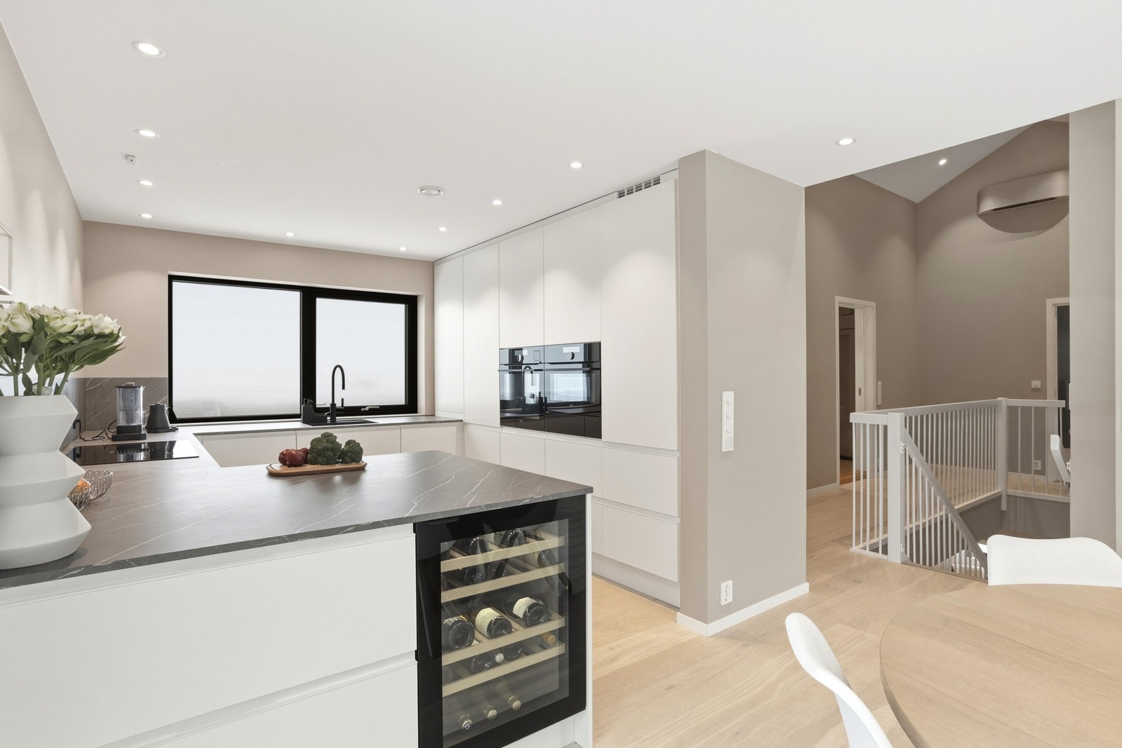 Stilren kjøkkeninnredning med glatte fronter og benkeplate med laminert overflate og underlimt kjøkkenvask med armatur Galleribilde