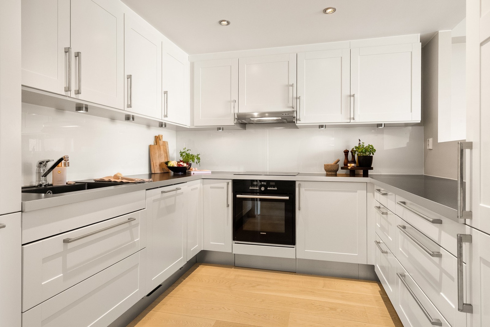 Innredningen har profilerte fronter i en lys hvit tone, kombinert med benkeplate i laminat og planlimt kum i kompositt. Galleribilde