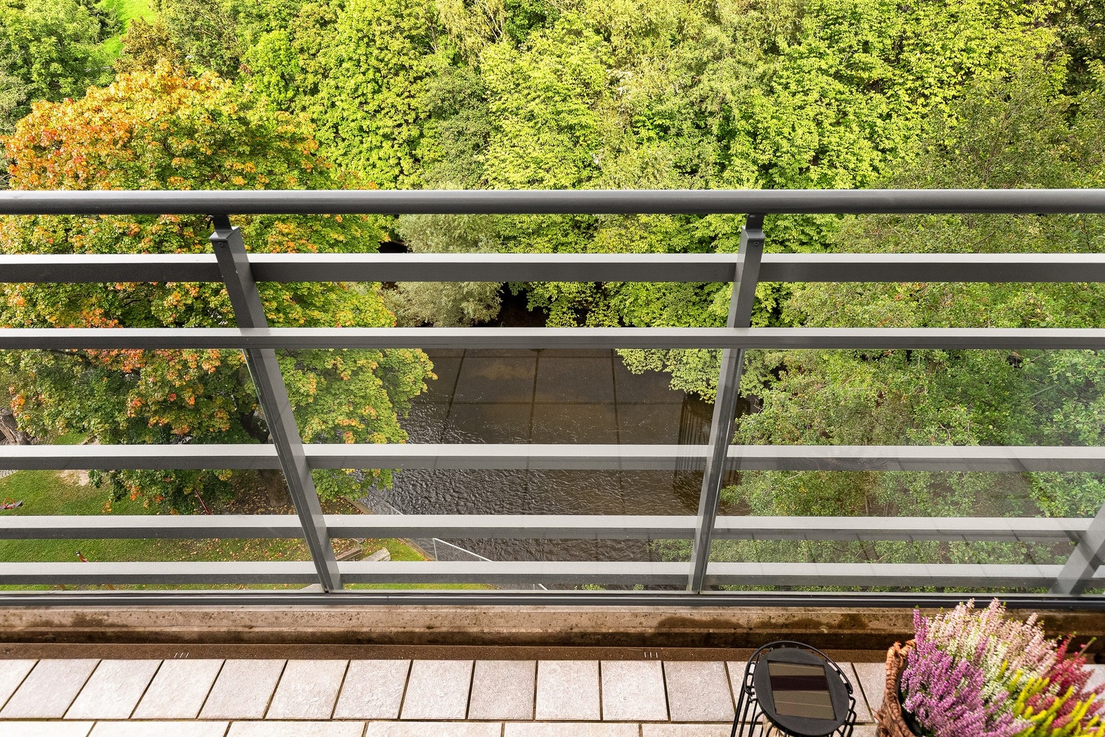 Uteplassen har et åpent utsyn ned mot Akerselva, omgitt av tette, grønne trær. Galleribilde