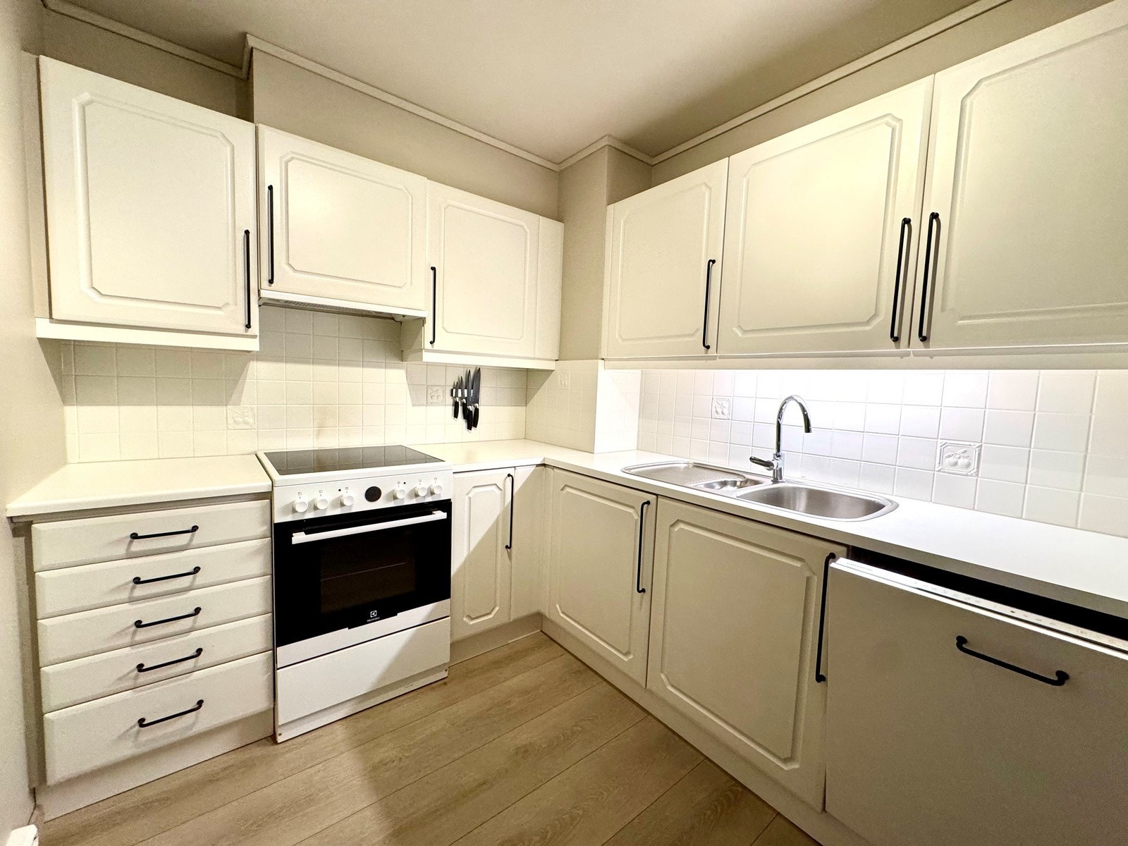 Lyst kjøkken med malte flater og hvitevarer inkludert Galleribilde