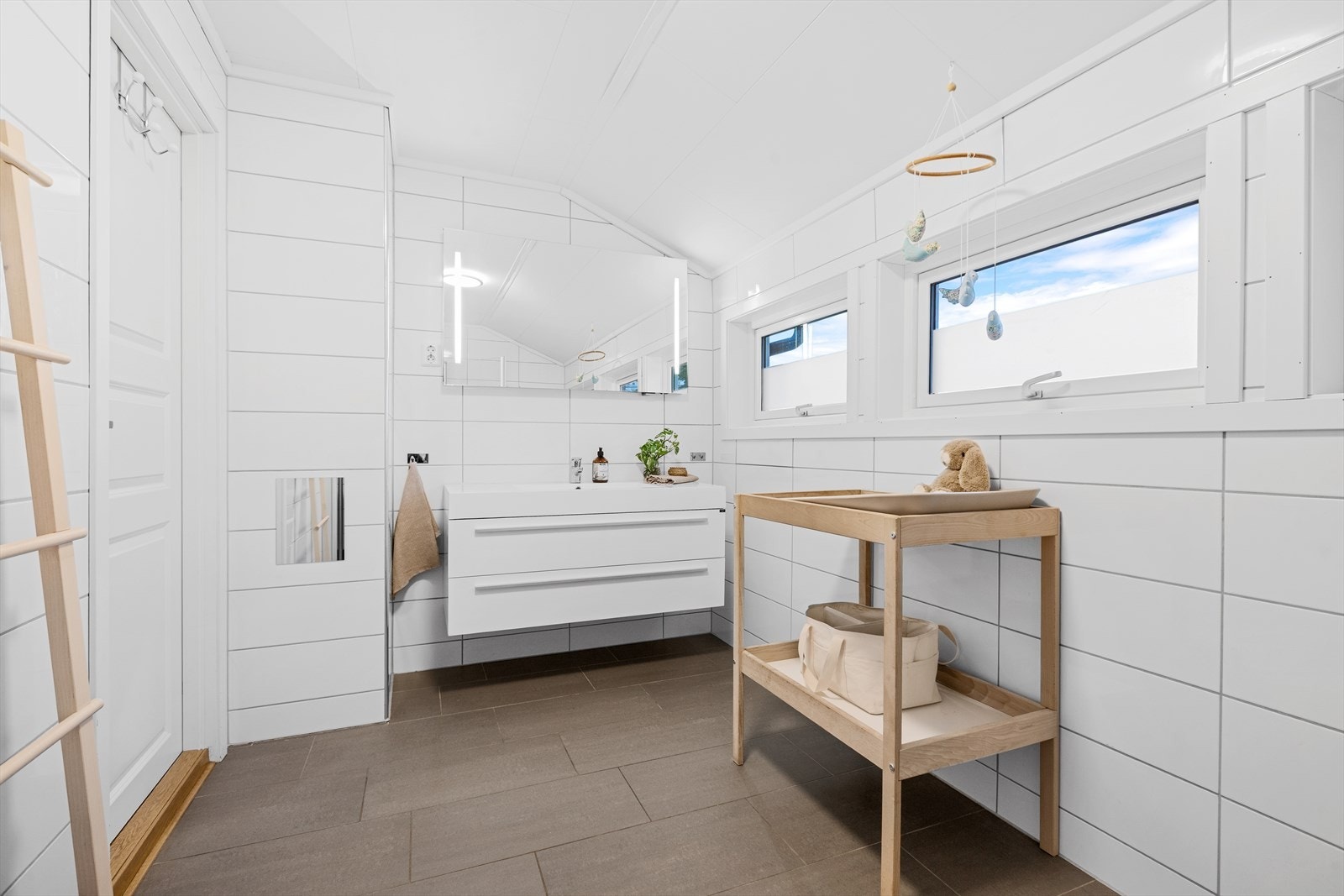 Badet har vask med underdkap og speil med integrert lys- videre er det dusjsone og vegghengt toalett Galleribilde