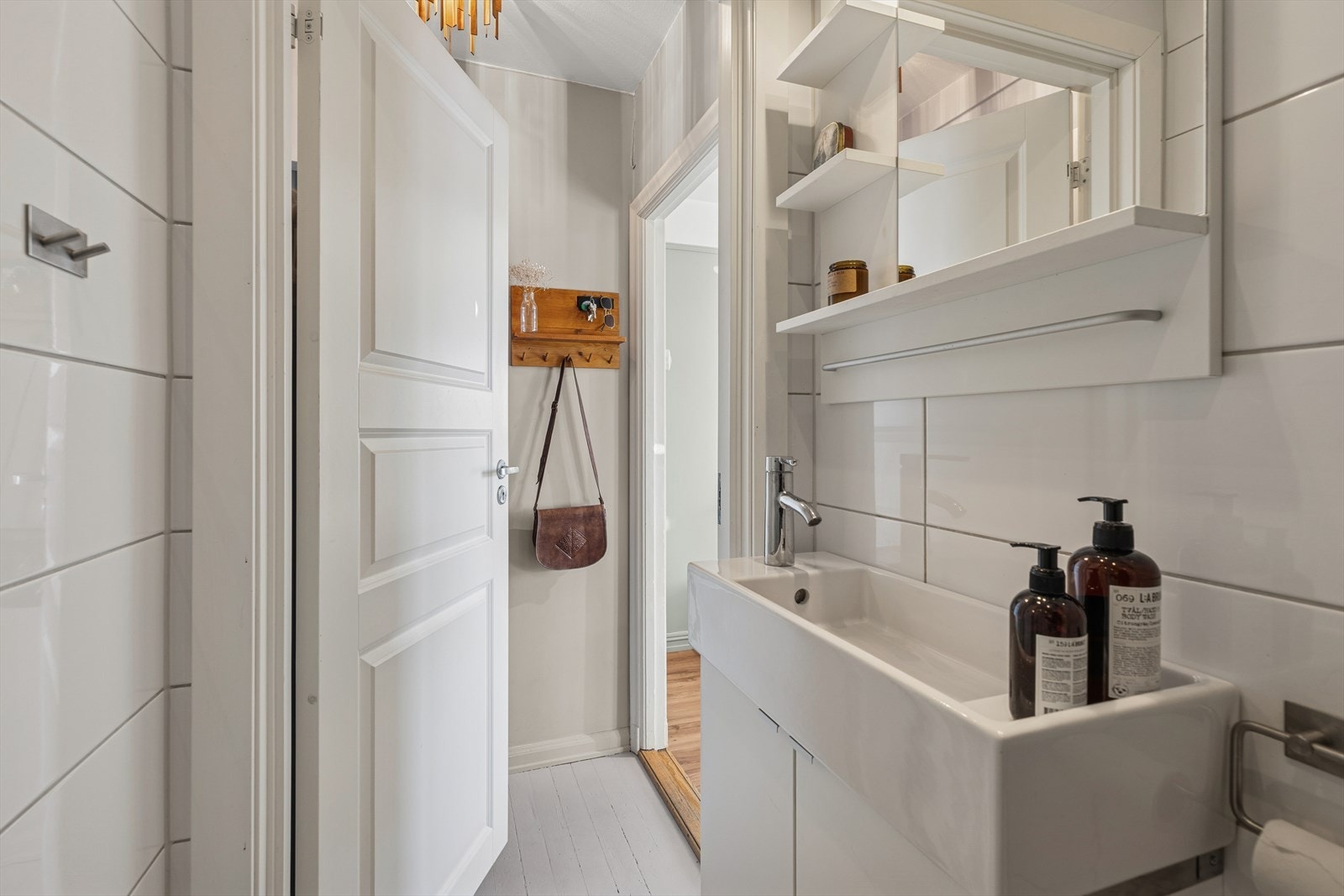 Pent, flislagt bad med dusjhjørne, servant med oppbevaring og toalett. Effektiv og praktisk utforming. Galleribilde