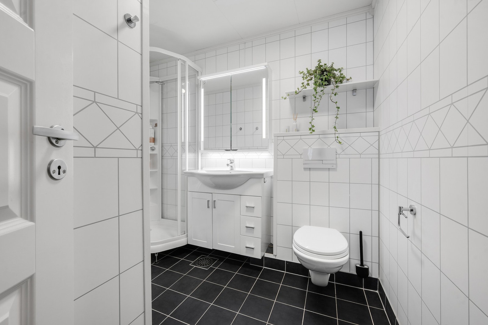 Pent oppgradert bad med mørke gulvfliser, lyse baderomsplater og en moderne baderomsinnredning. Galleribilde