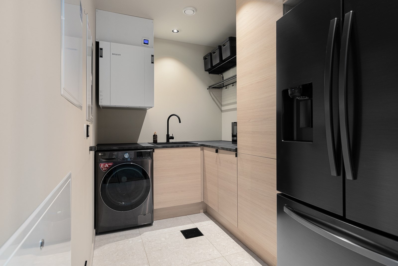 Lekkert og praktisk vaskerom med flislagt golv og varmekablar. Her er benkeinnredning med mykje god oppbevaringsplass samt opplegg til vaskemaskin. Galleribilde