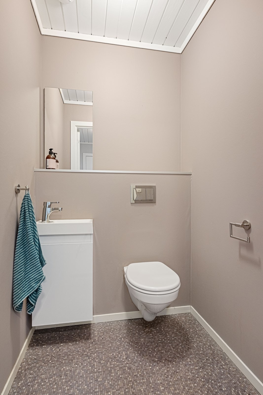 Toalettrommet inneholder vegghengt wc og servant med underskap. Galleribilde