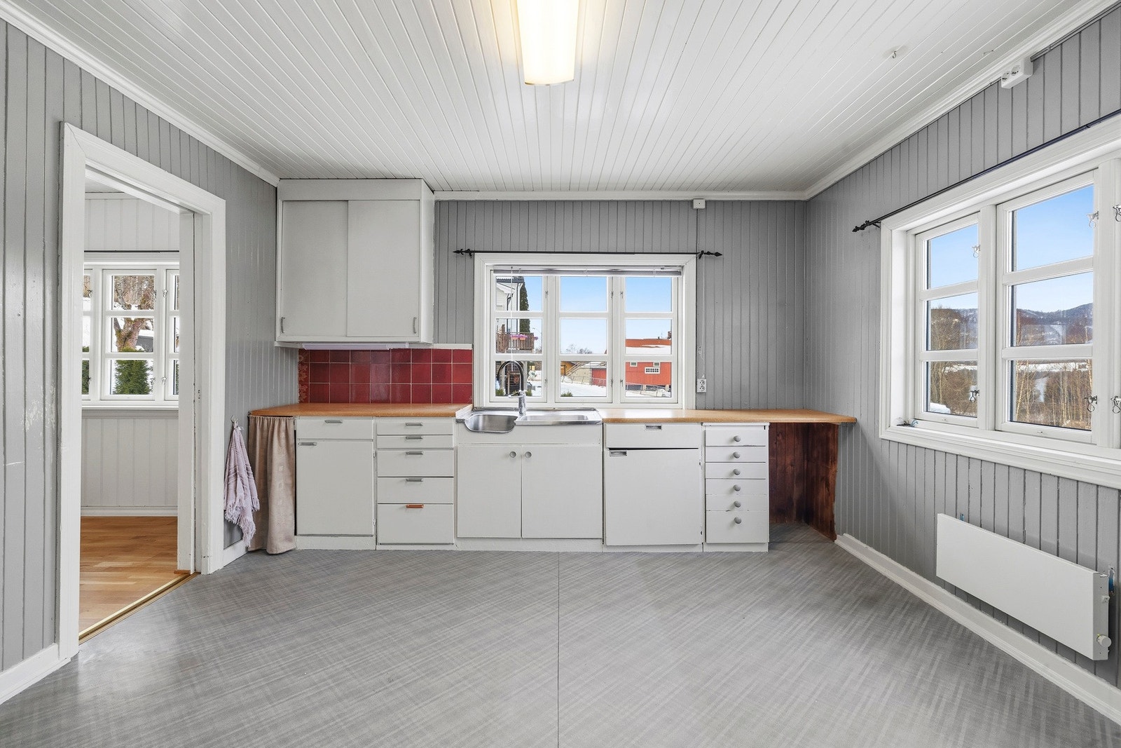 Eldre og lyst innredet kjøkken. Mye vinduer som gir rikelig med naturlig lys. Galleribilde