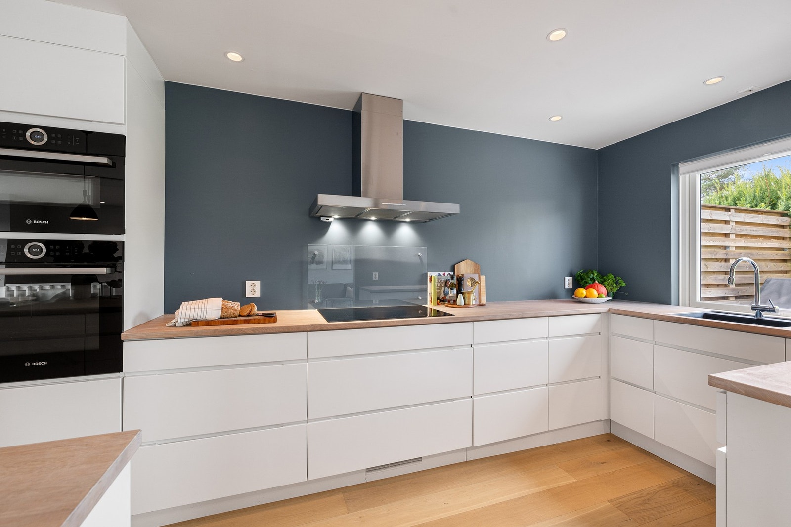 Pent og tidsriktig kjøkken fra Kvik med hvite, glatte fronter og heltre benkeplate som gir et varmt og moderne uttrykk. Galleribilde