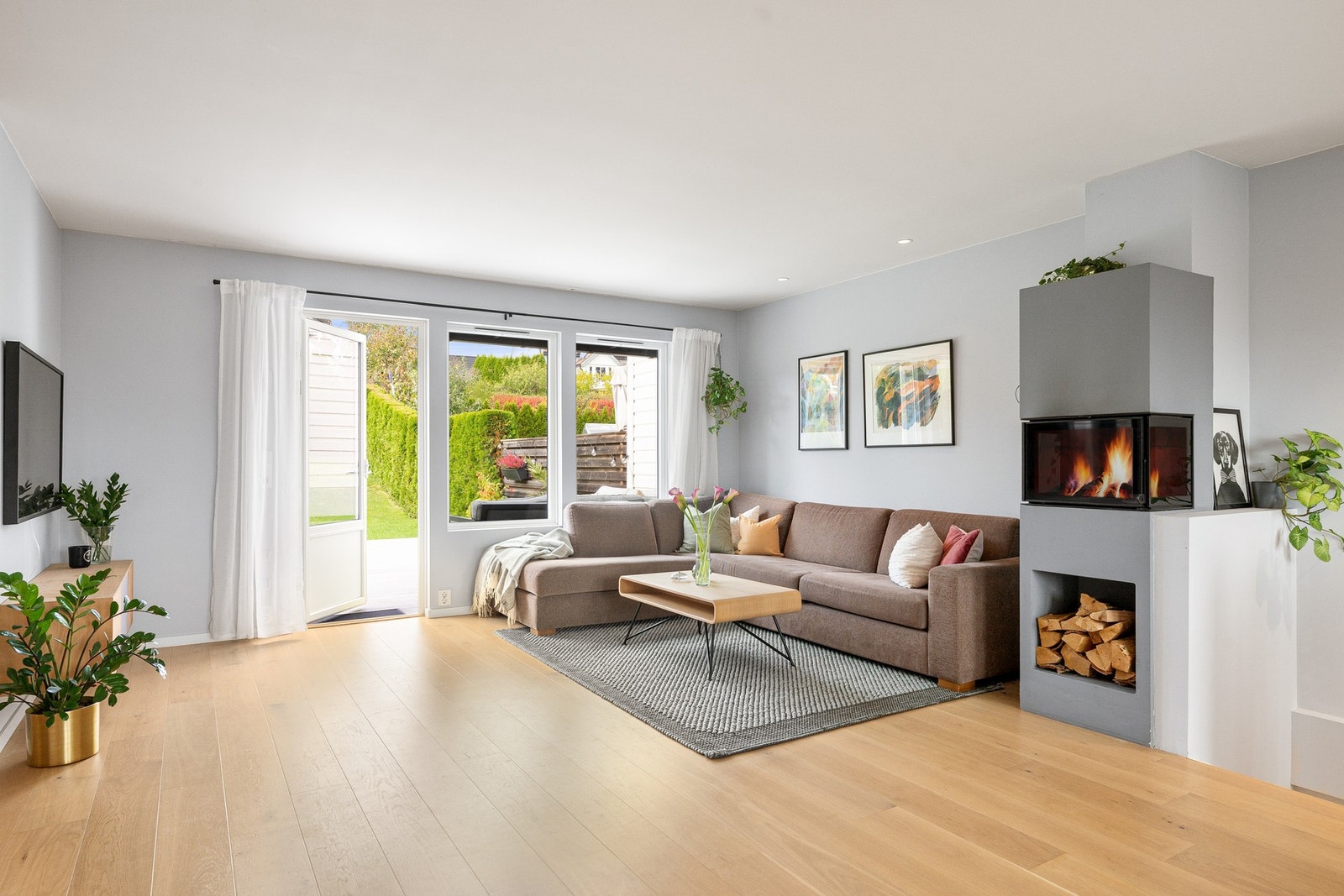 Stilren peis fra Nordpeis modell Praha med flammeinnsyn fra tre sider og praktisk vednisje, installert i 2018. Galleribilde