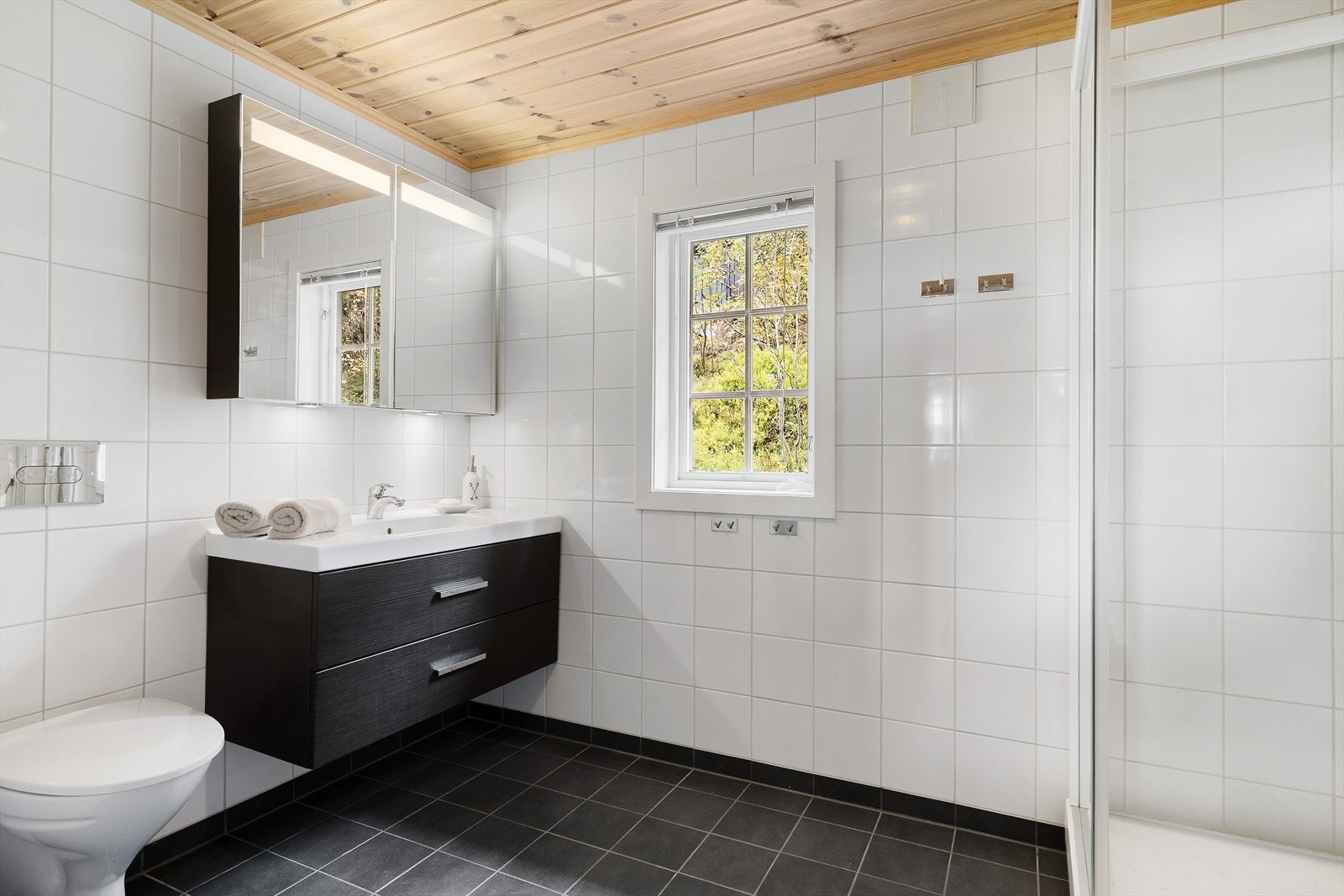 Lyst og praktisk bad med flislagte vegger og gulv, utstyrt med elektriske varmekabler. Galleribilde