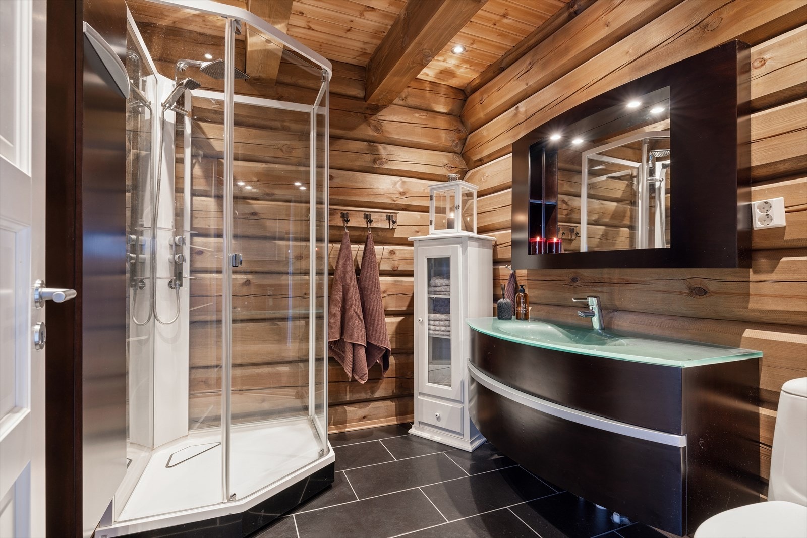 Sanitærutstyret inkluderer gulvmontert toalett, heldekkende servant med ettgreps blandebatteri og et moderne dusjkabinett med glassdør, regnfallsdusj og separat hånddusj Galleribilde