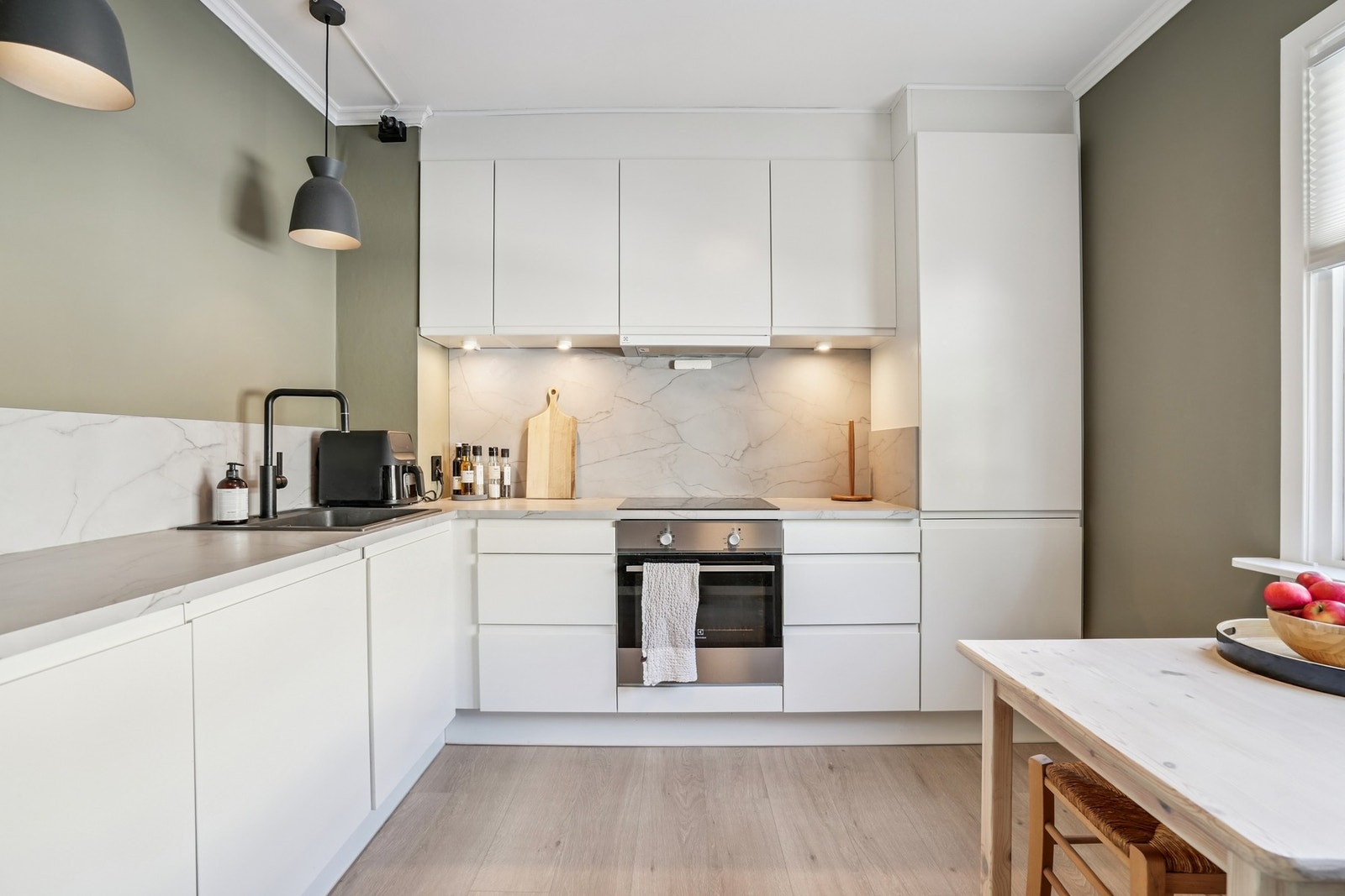 Innredningen har glatte hvite fronter og laminat benkeplate, spotter under overskap. Galleribilde