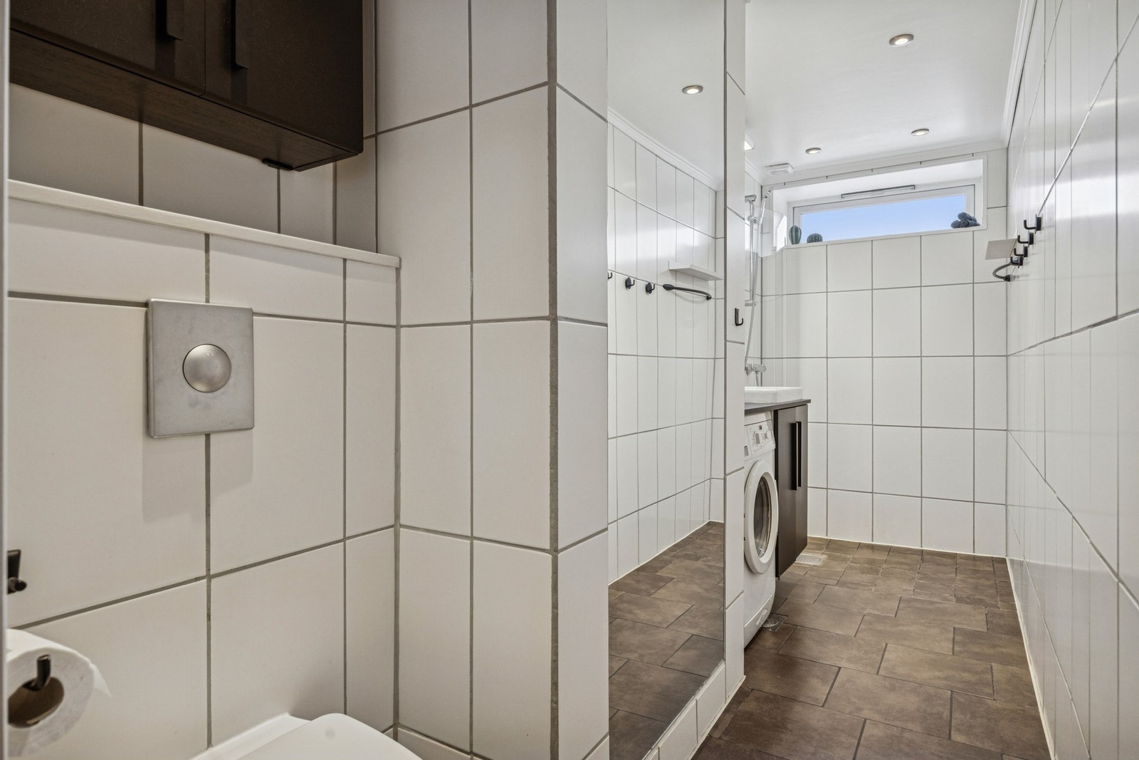 Flislagt bad med en praktisk utforming med separat dusjsone og gode oppbevarings muligheter. Galleribilde