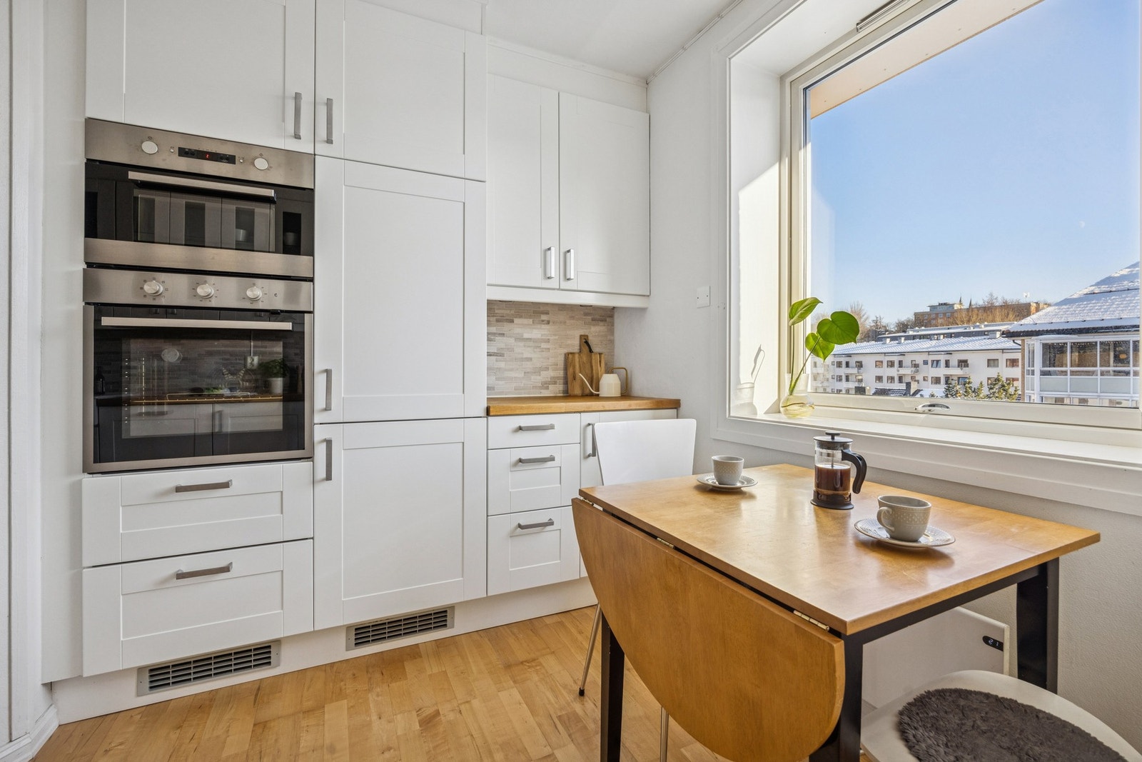 Lyst og tidløst kjøkken med god skapplass og naturlig spiseplass ved vinduet - perfekt for rolige morgenstunder. Galleribilde