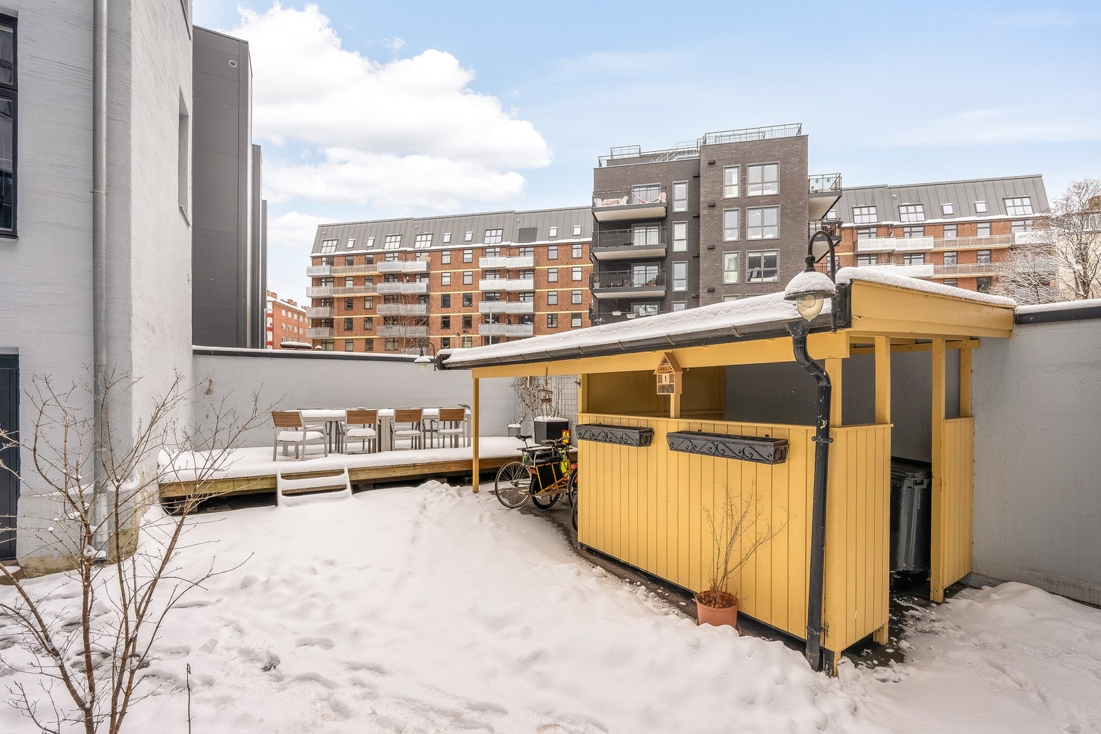 Felles, asfaltert bakgård med sittegruppe på terrasseplatting. Galleribilde