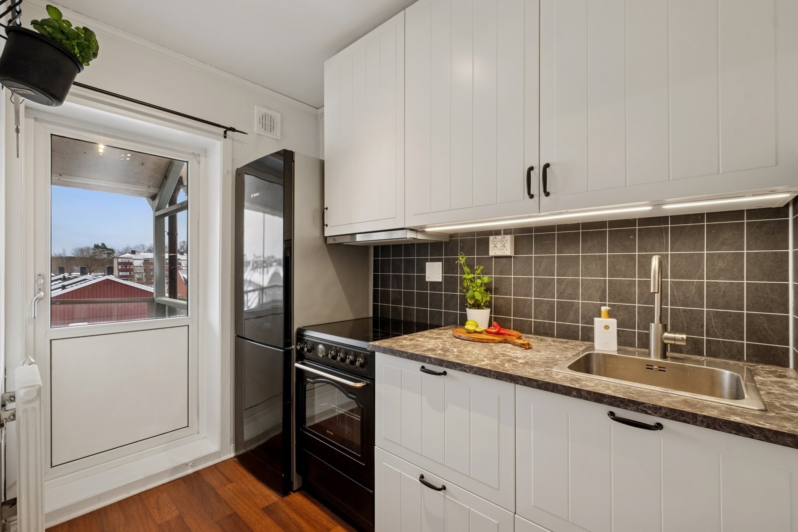 Lyst og praktisk kjøkken med god skapplass og utgang til solrik balkong Galleribilde