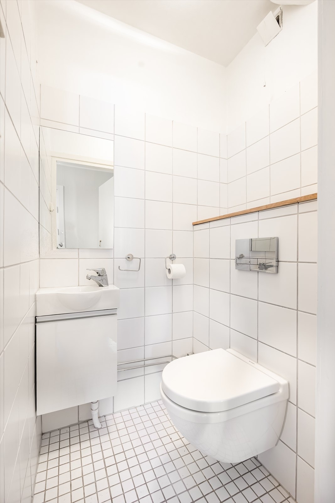 Gjestetoalettet har praktisk plassering i tilknytning til entréen. Toalettrommet har vegghengt innredning med heldekkende servant og vegghengt toalett med innebygget sisterne. Galleribilde