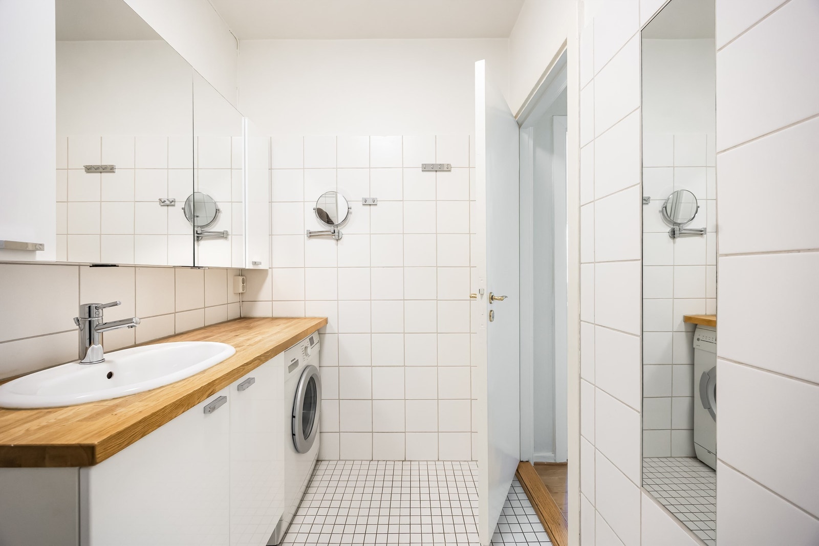 Videre er det overskap med speildører og stikkontakt på vegg over benkeplate. Det er opplegg for vaskemaskin. Galleribilde