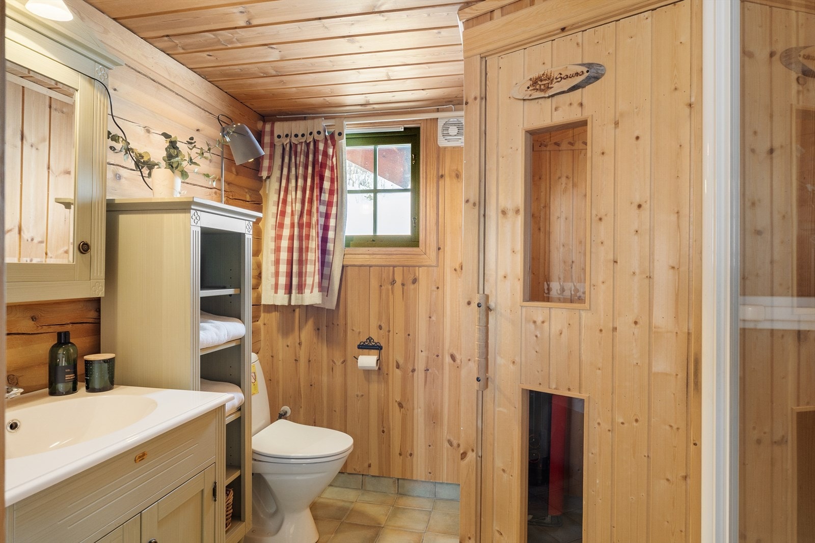 Badet har flislagt gulv med elektriske varmekabler. Rommet er innredet med servant, toalett og dusjkabinett. Vegger er kledd med panel og tømmer. Galleribilde