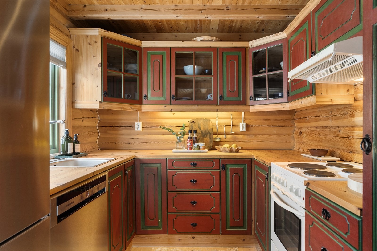 Pen og praktisk innredning med profilerte fronter og benkeplate i heltre. Frittstående hvitevarer. Ventilator med avtrekk ut. Galleribilde