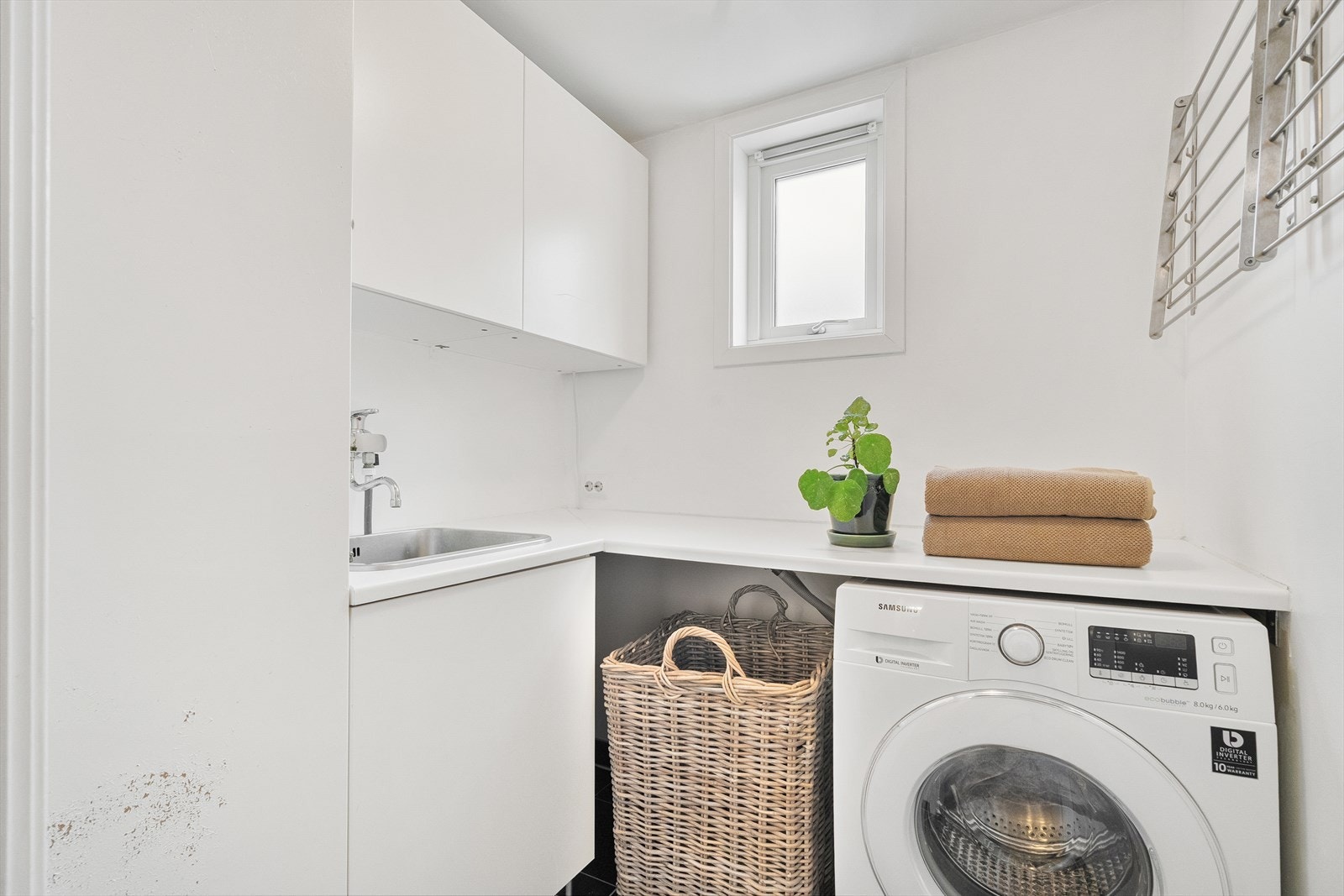 Fra bad har man tilkomst til praktisk vaskerom med gjennomtenkte løsninger som gjør hverdagen enklere. Her er det god skapplass, benkeplate, utslagsvask og opplegg til vaskemaskin. Galleribilde