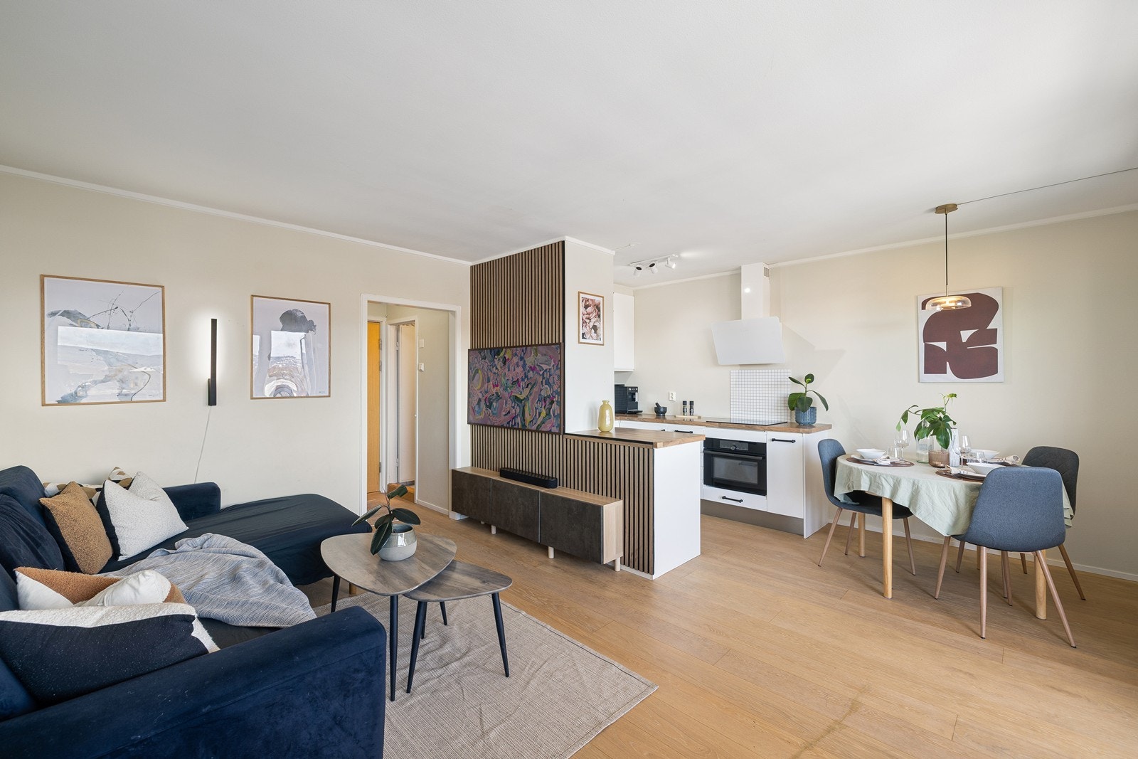 Åpen planløsning mellom stue og kjøkken, der en øy fungerer som romdeler og gir kjøkkenet en egen, definert sone. Galleribilde