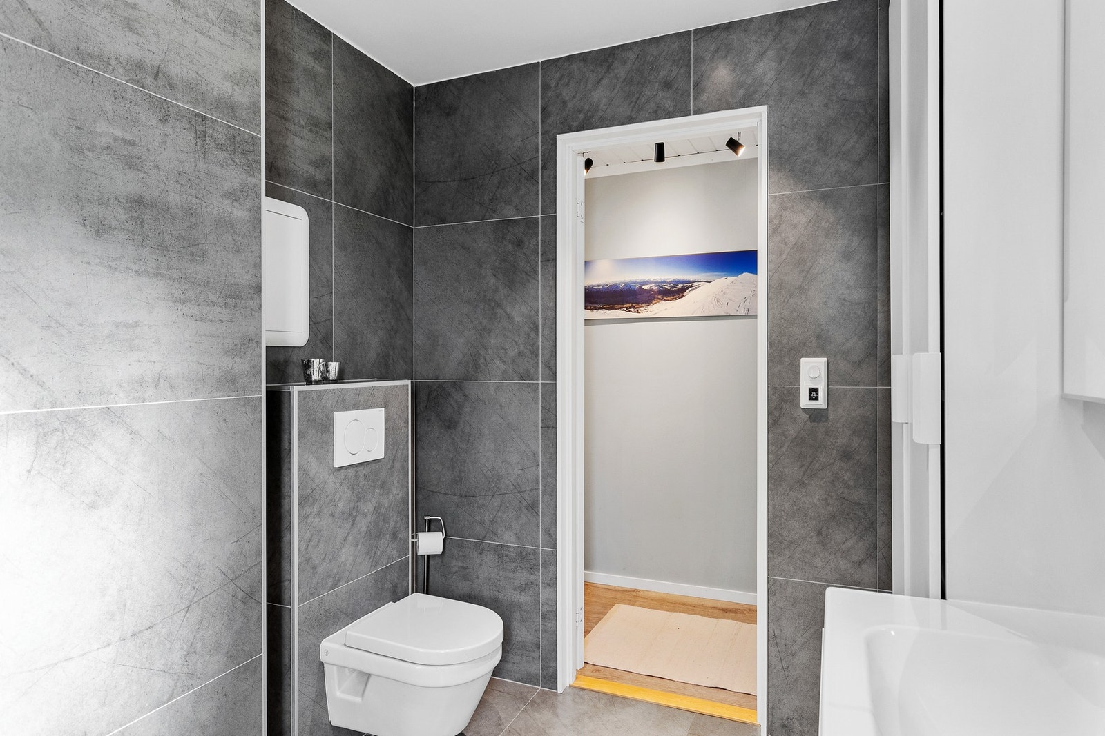 Badet har veggmontert wc, dusjnisje, servant og rikelig med skapplass. Galleribilde