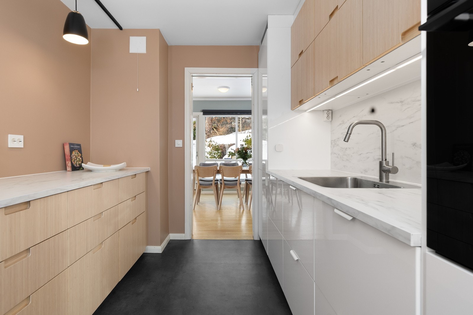 Det er skap helt opp til taket og abeidsbenk med vaskekum og integrerte hvitevarer på ene siden og god arbeidsbenk med skuffer på andre siden Galleribilde