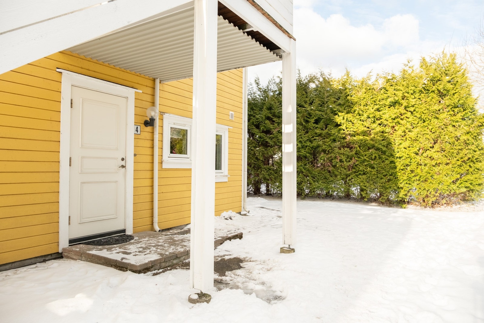 Sommerstid er det sol foran inngangspartiet på morgen/formiddag. Asfalt er lagt foran inngangssiden og på gangvei helt frem til parkeringsområdet. Galleribilde