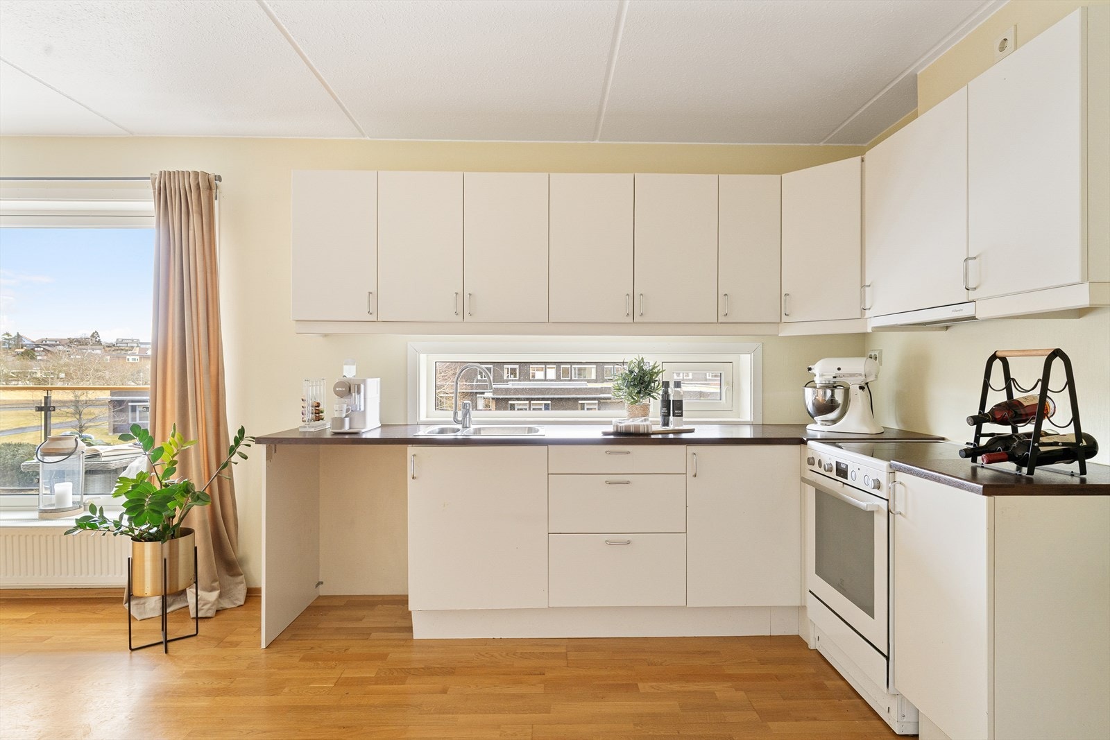 Lekkert kjøkken med lyse flater og mørk benkeplate som skaper en fin helhet i utrykket. Galleribilde