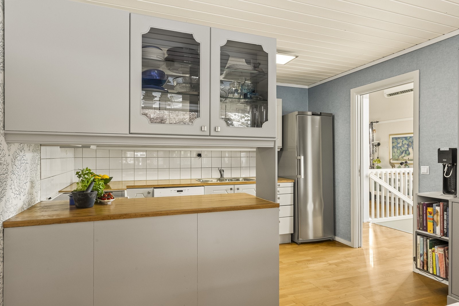 Innredningen på kjøkken består av grå, profilerte fronter kombinert med laminert benkeplate, samt flislagt felt mellom benkeplate og overskap, som er lett å holde rent. Galleribilde