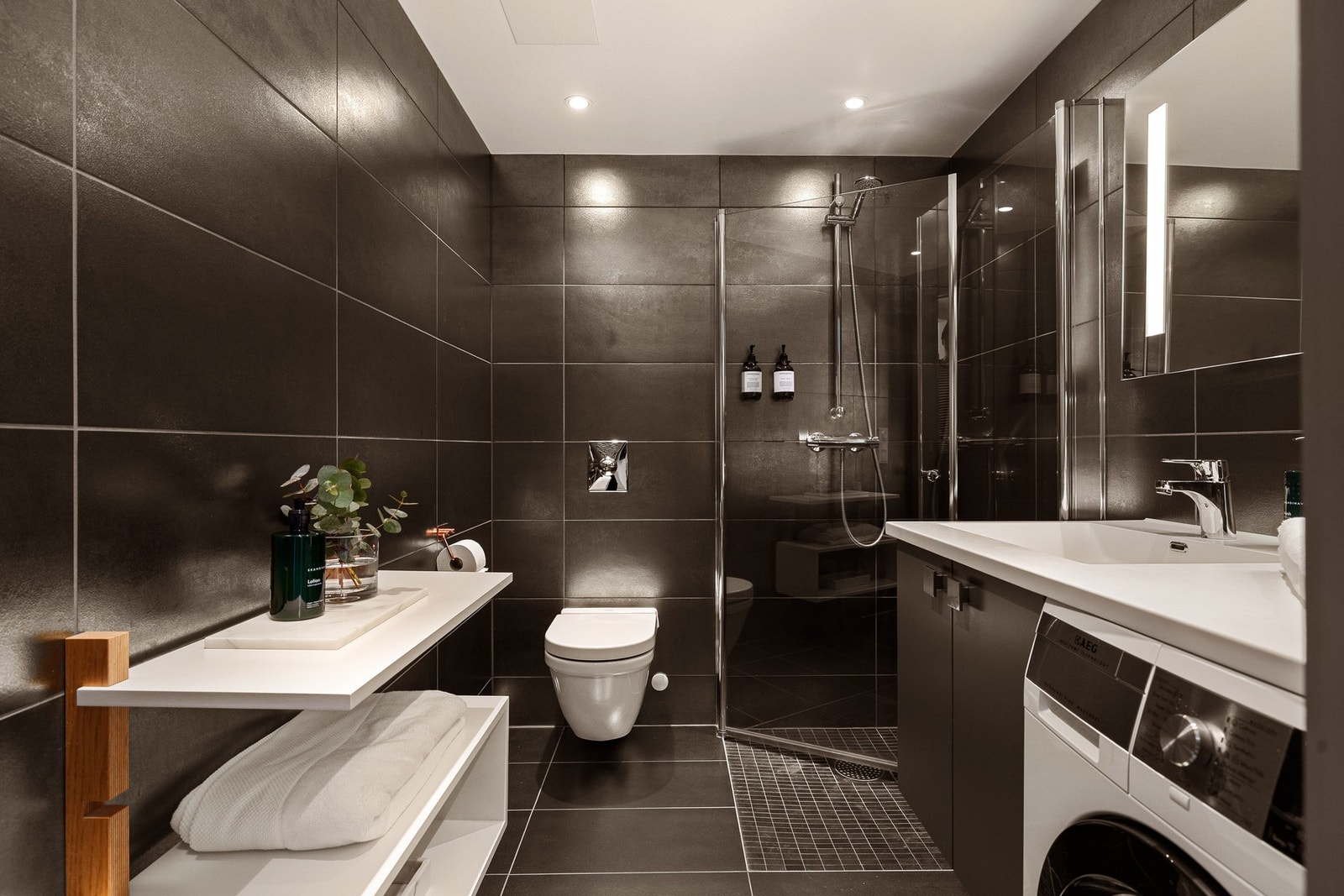 Leiligheten har et stilrent og moderne baderom fra byggeåret 2015. Baderommet har mørke fliser på gulv og vegger, elektrisk gulvvarme, downlights i himlingen og mekanisk avtrekksventilasjon. Galleribilde