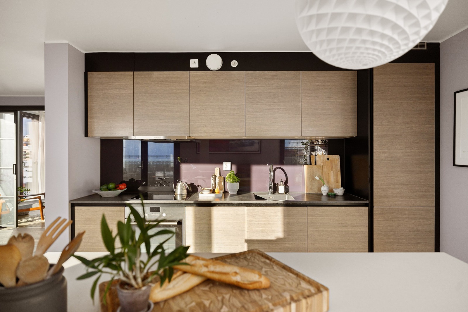 Kjøkkeninnredningen har tidsriktige glatte fronter og laminert benkeplate med underlimt oppvaskkum. Praktisk med glassplate i benkeryggen og belysning under overskapene. Galleribilde