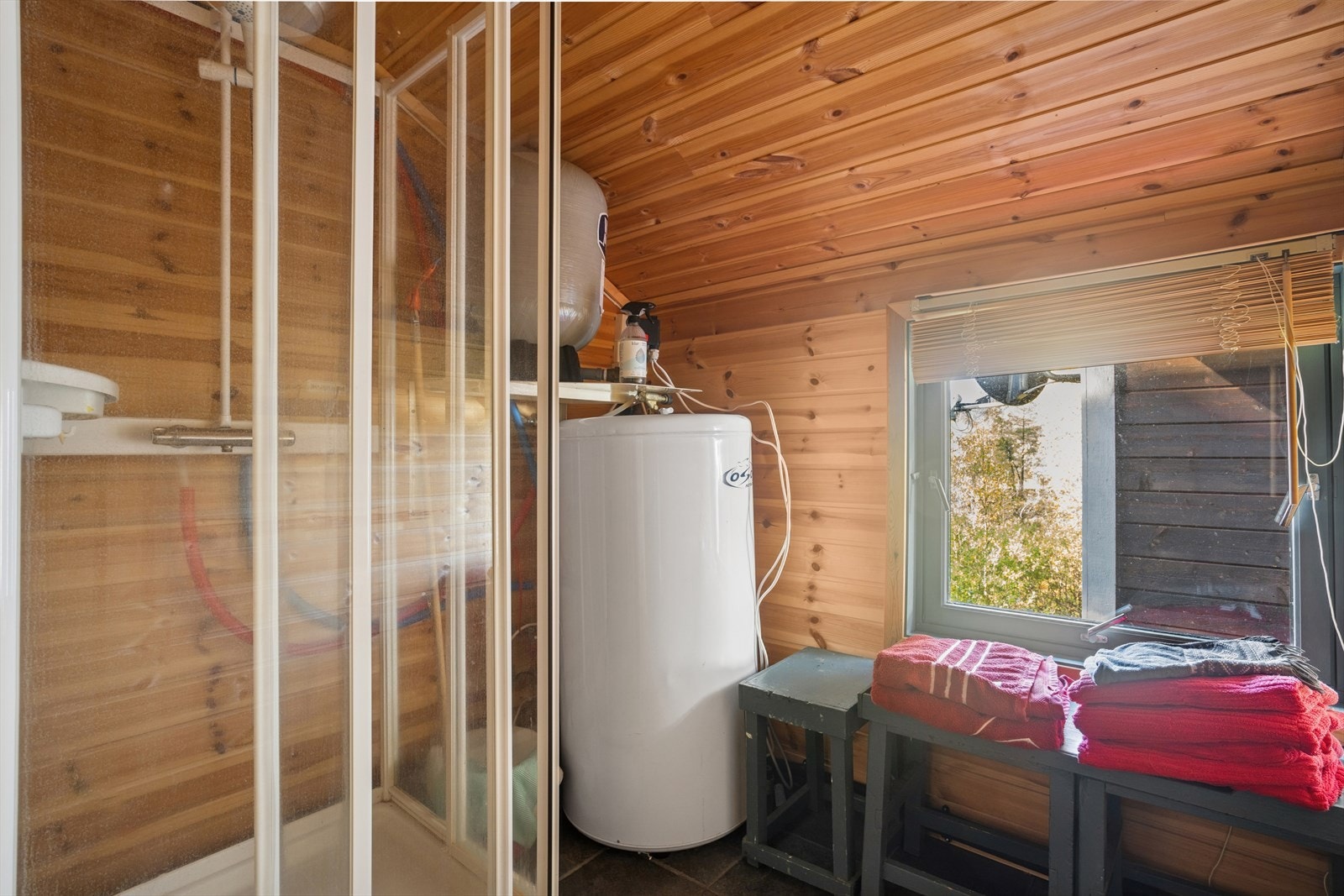 Det er dusjkabinett og varmtvannstank plassert på badet med varmekabler. Galleribilde