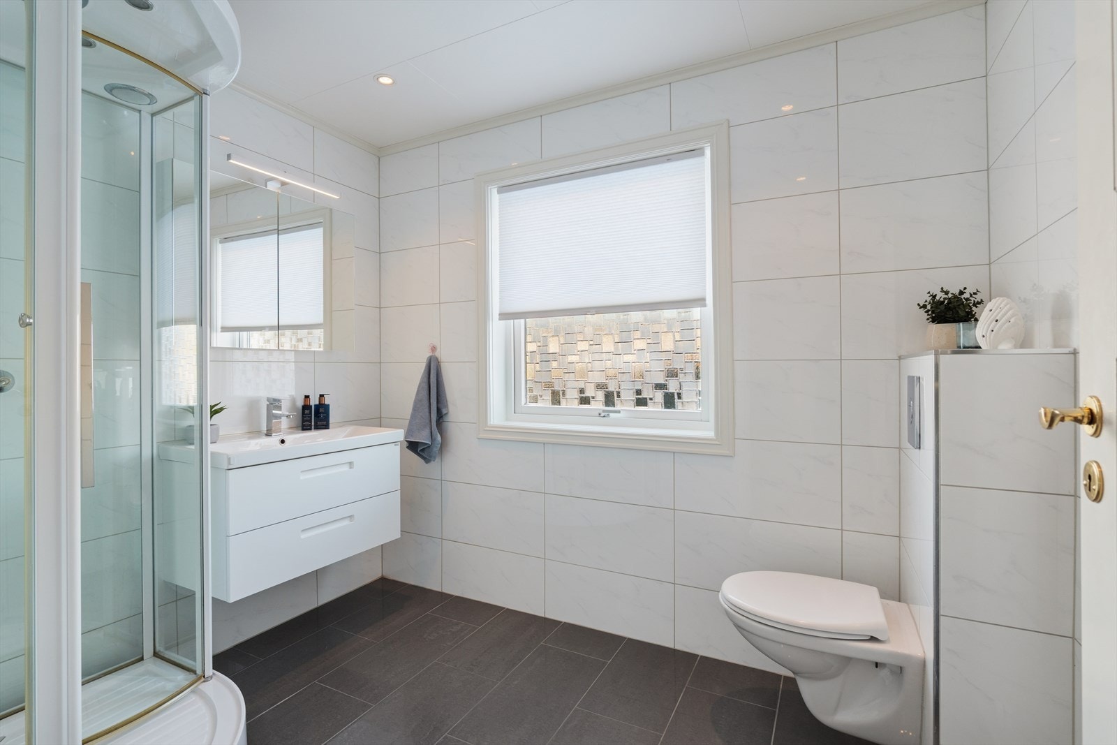 Pent bad fra 2016 med veggmontert wc, romslig servantskap og dusjkabinett. Galleribilde