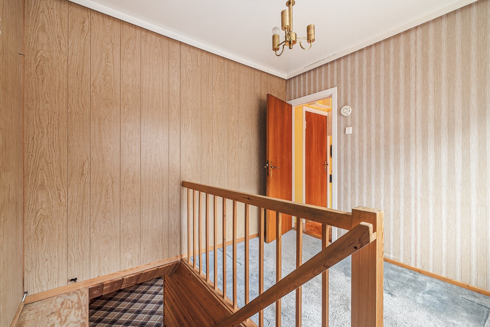 Trappegang (tidliger brukt som soverom) med teppe på gulv, tapet og tynnpanel på vegger
og malt lerret i himling. Galleribilde