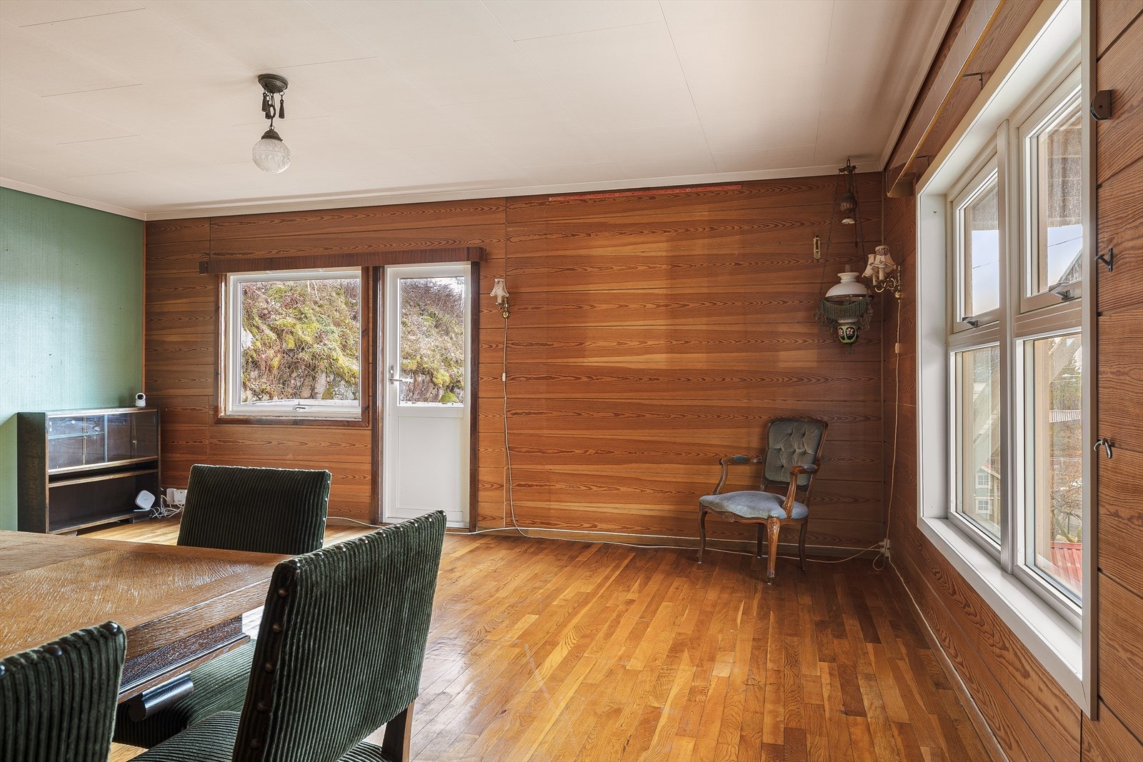 Stue på 30m². Her er parkett på gulv, malt strie og panel på vegger
og takplater i himling. Galleribilde