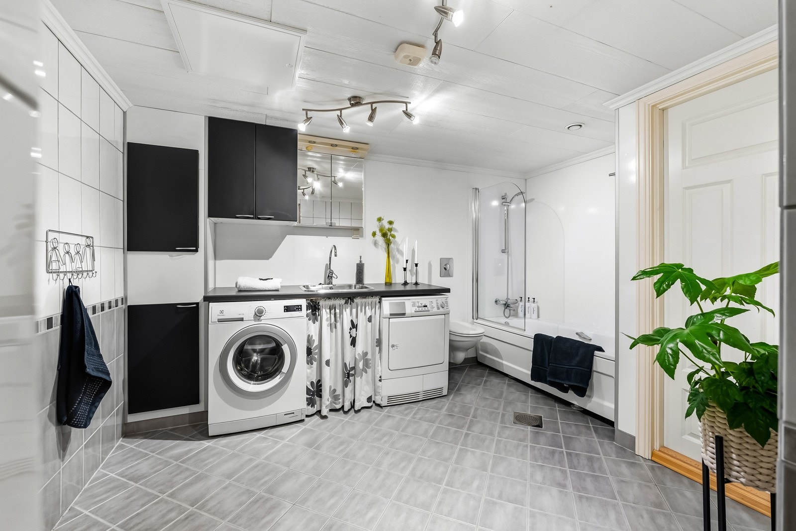 Bad u.etg. hoveddel. Baderomsinnredning bestående av veggskap og skittentøysjakt skjult i høyskap. Dusj i badekar, skyllekum og opplegg for vaskemaskin. Galleribilde