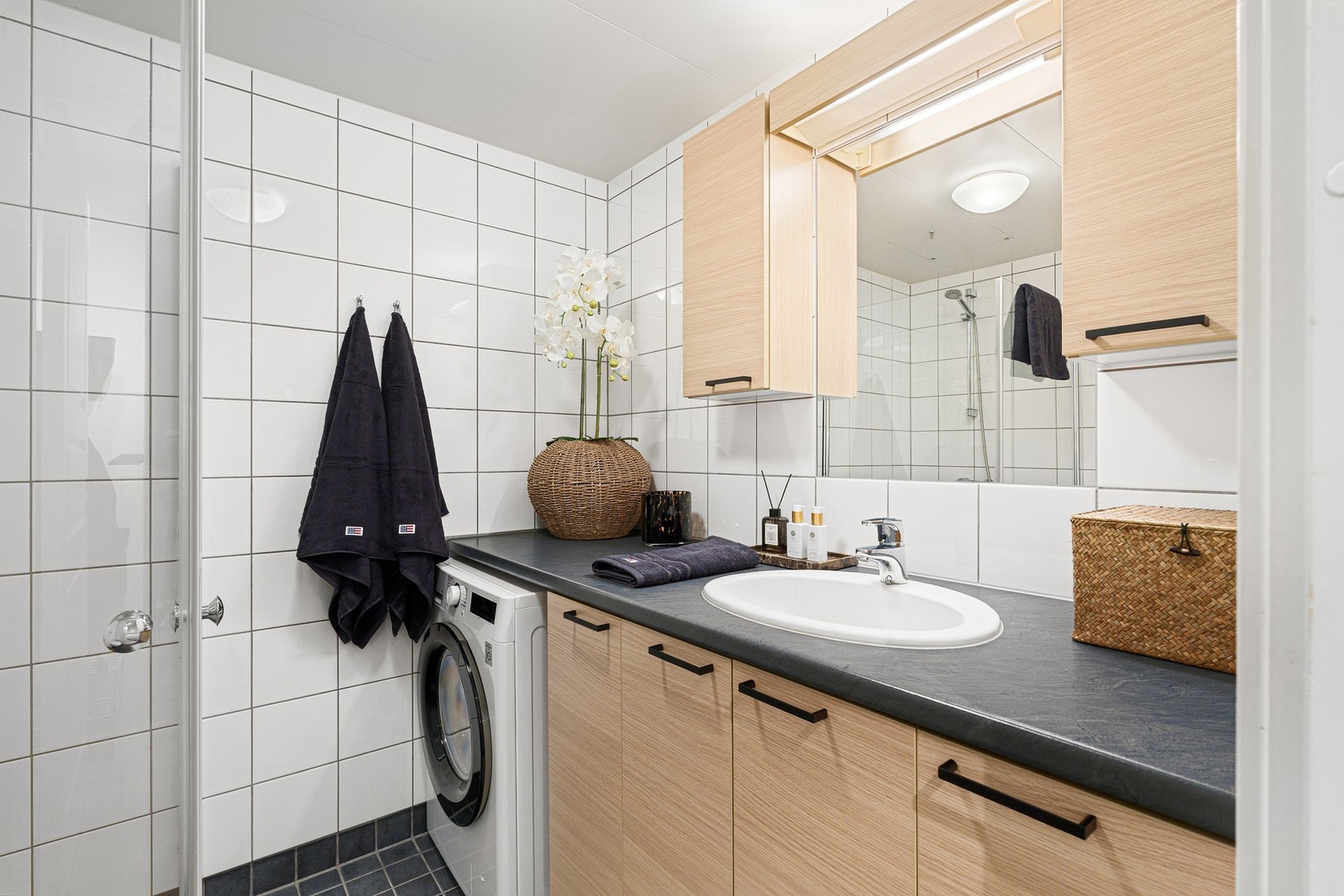 Innfellbare dusjdører gir ekstra gulvplass når de ikke er i bruk. Badet har også opplegg for vaskemaskin. Galleribilde