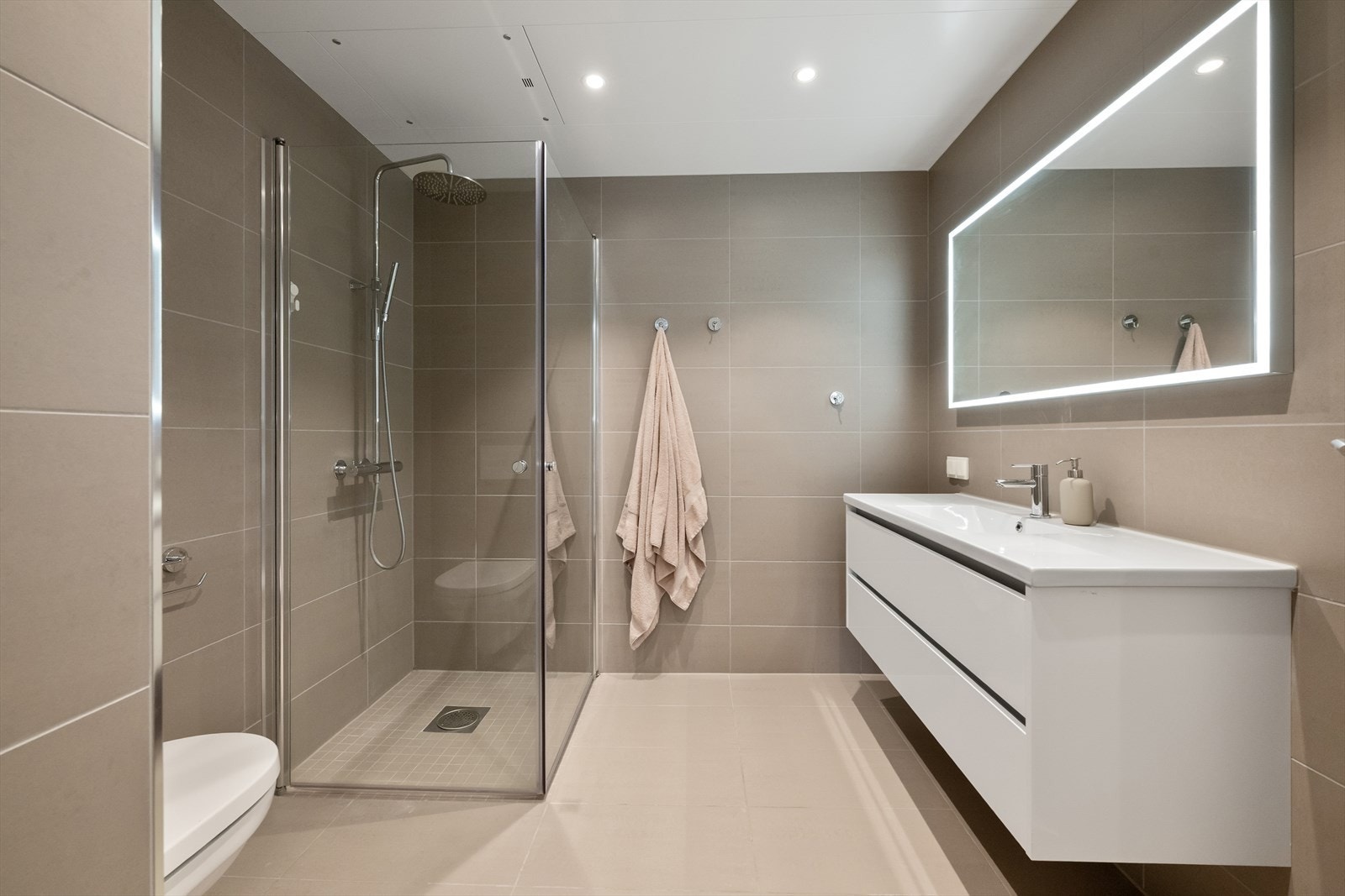 Pent helfliset bad utført med varme i gulv, vegghengt toalett, dusjnisje og servant. Galleribilde