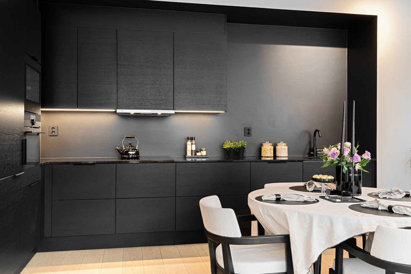 Kjøkkenfrontene er av eikefiner i glatt, mørk utførelse, kombinert med en solid benkeplate i granitt Nero Assoluto. Galleribilde