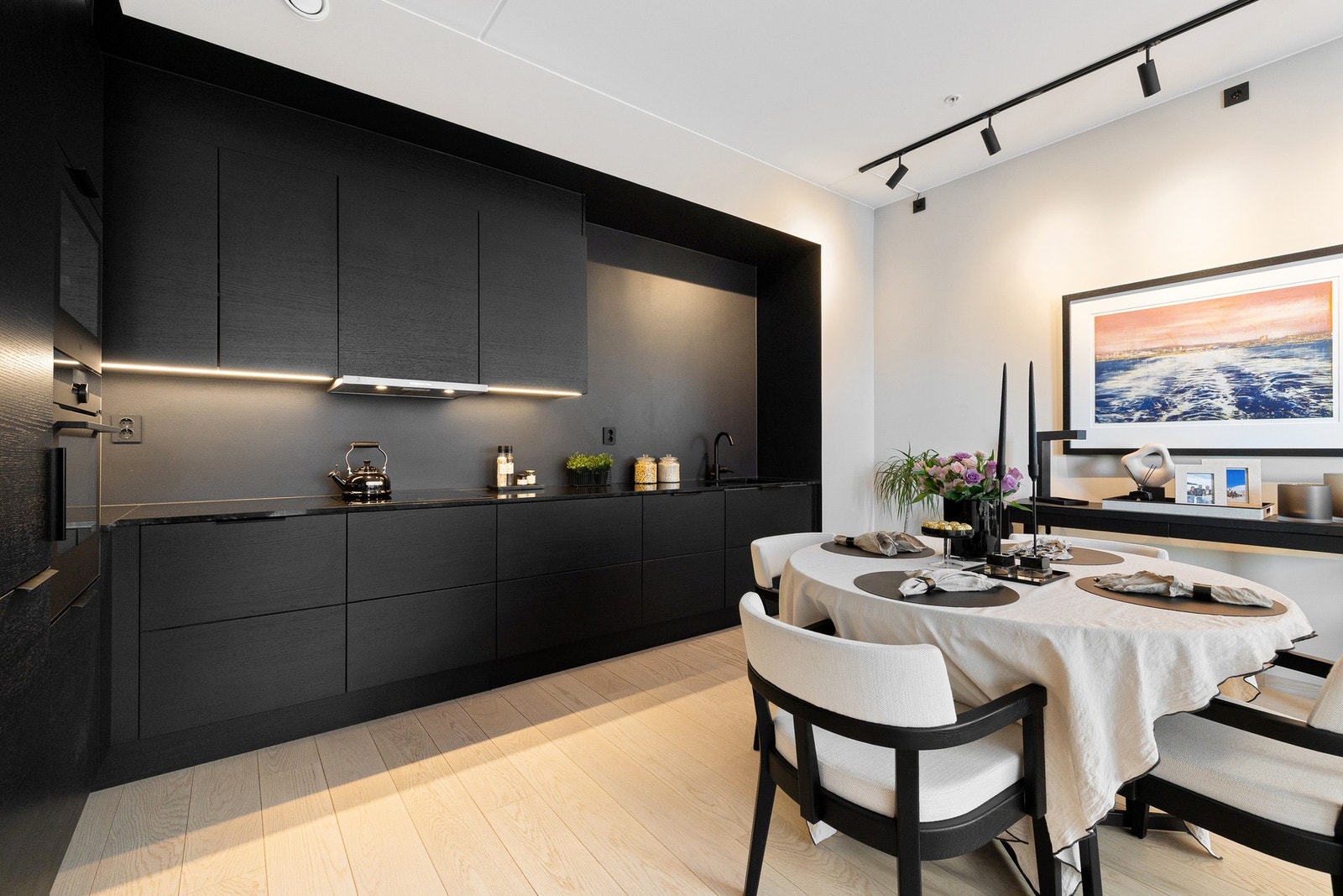 Veggen mellom overskap og benkeplate er malt i dempet sort (S 8500-N fra Jotun), nøye tilpasset for å matche kjøkkeninnredningen. Galleribilde